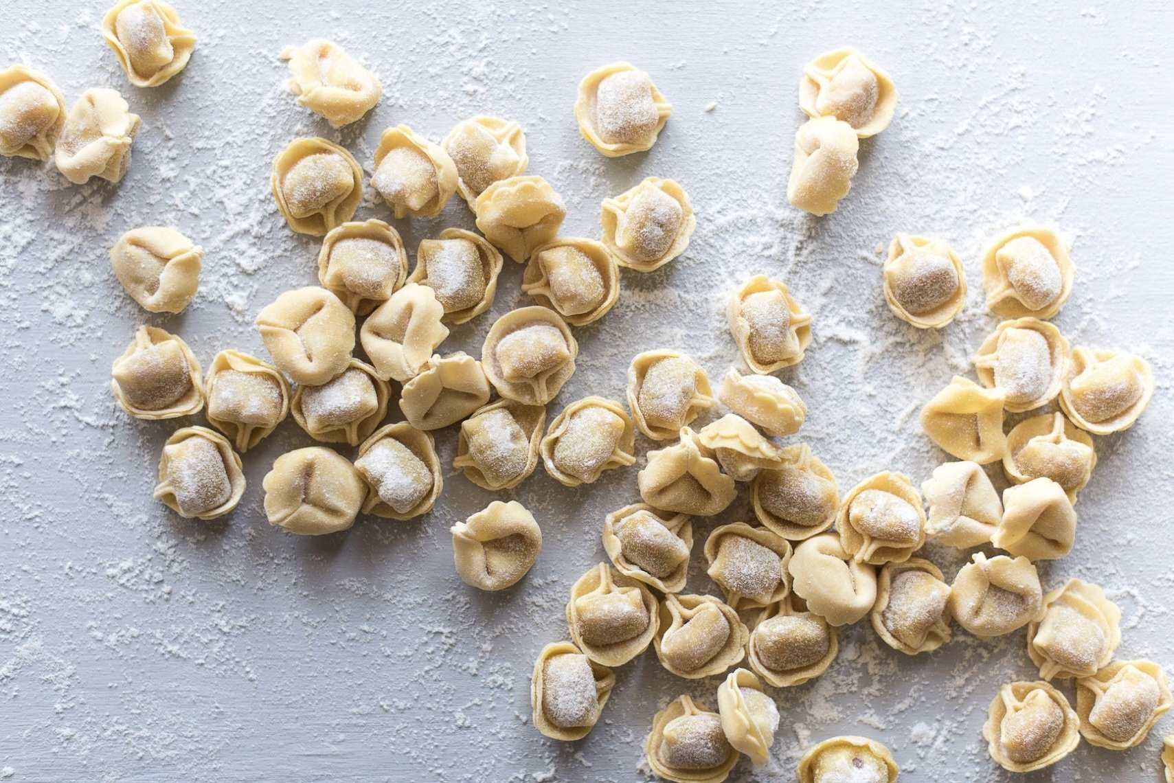 Tortellini freschi disposti su una superficie con farina.