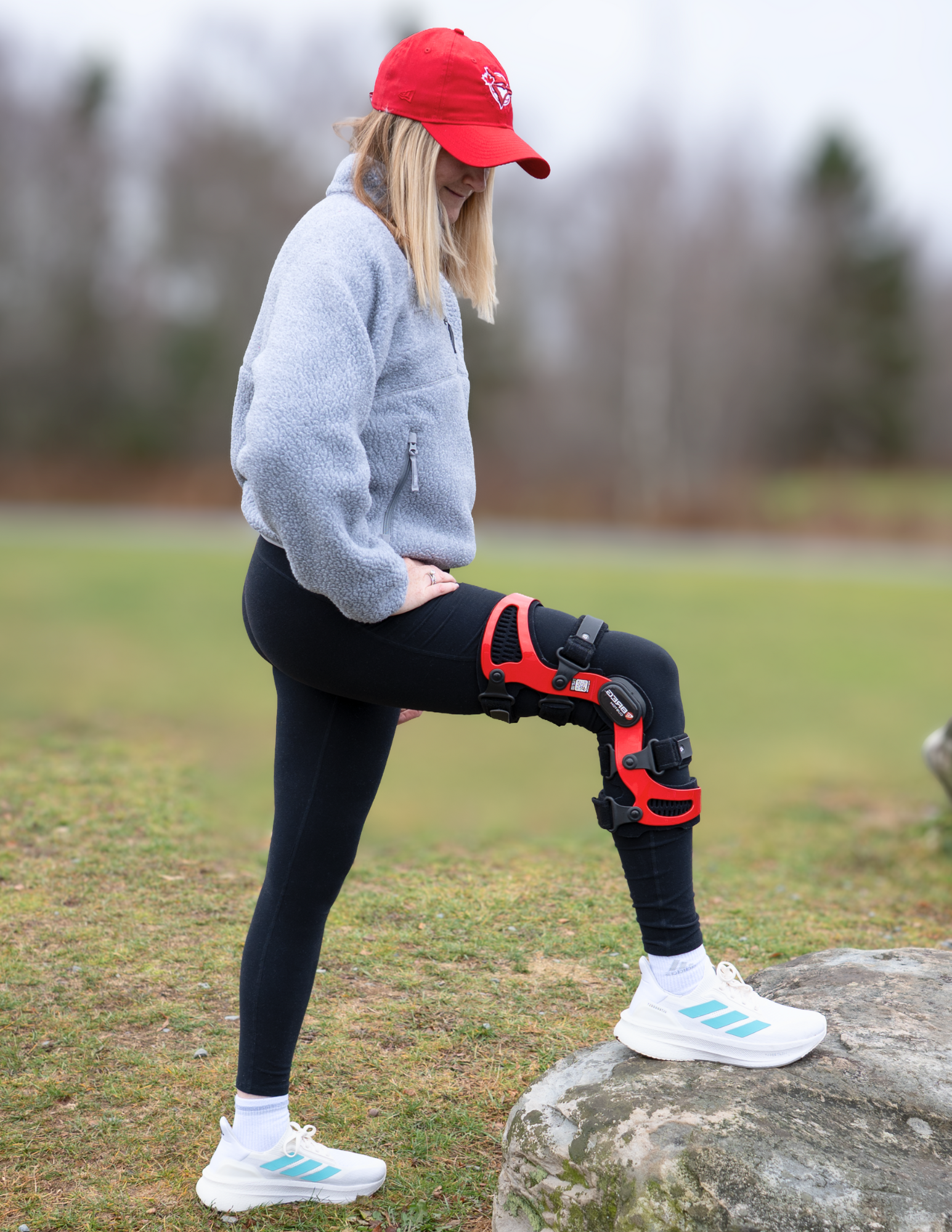 Person adjusting an orthopaedic knee brace with metal hinges and straps for stability and support