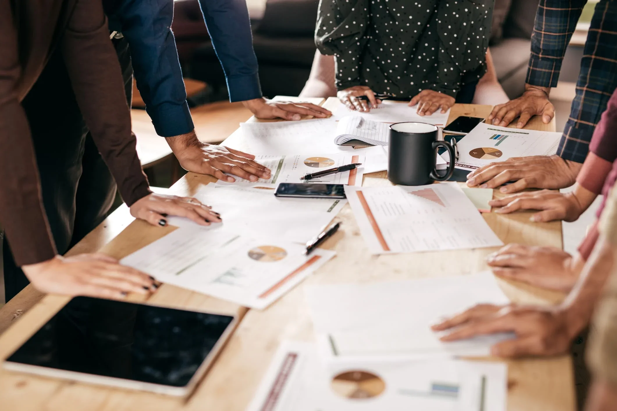 People gathered around a conference table reviewing documents and charts.