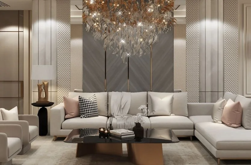 Elegant living room with white sofas, decorative pillows, a black coffee table, a table lamp, and a modern chandelier ceiling light.