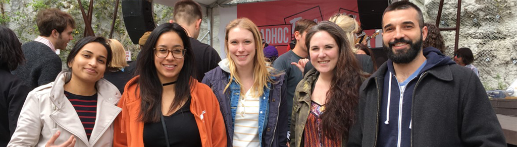Group of five young adults smiling outdoors at a casual gathering.