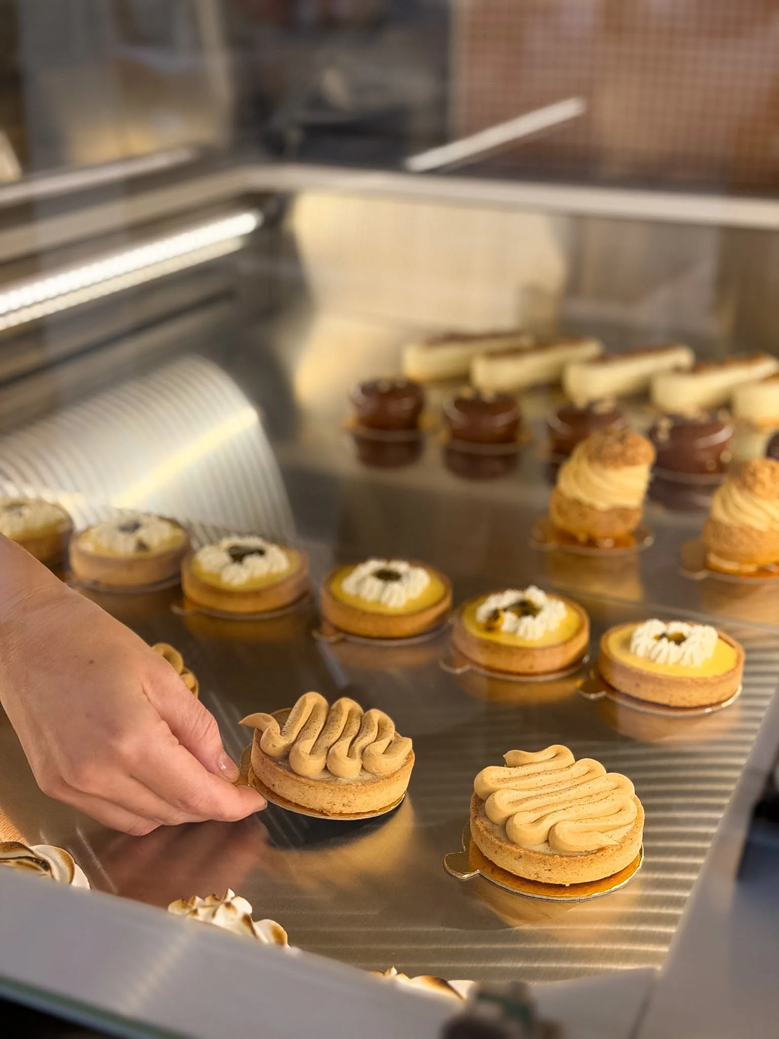 Gâteaux et biscuits en vitrine, avec une main tenant un biscuit décoré.