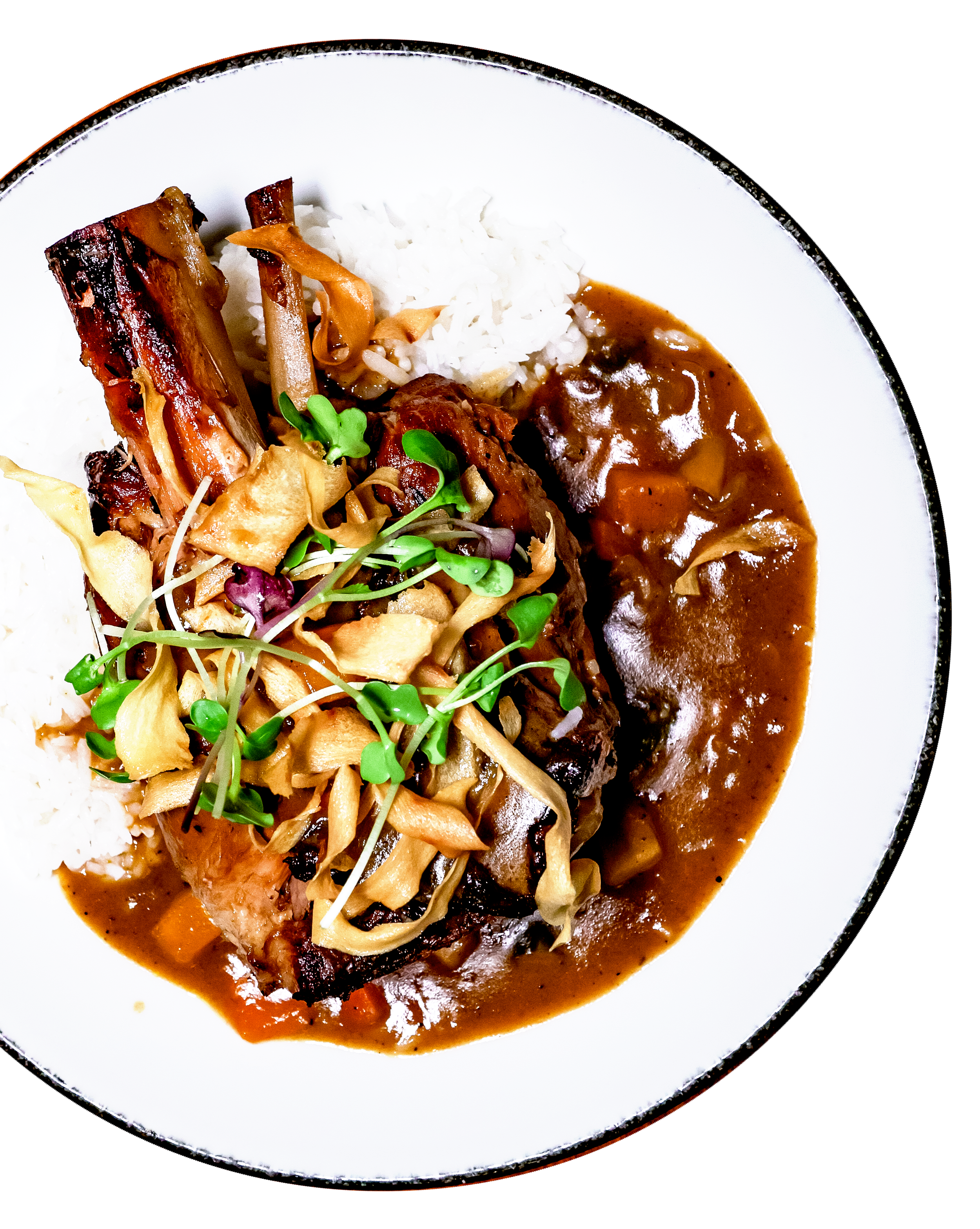 Plate of rice, beef with gravy, roasted ribs, and sautéed vegetables topped with microgreens.