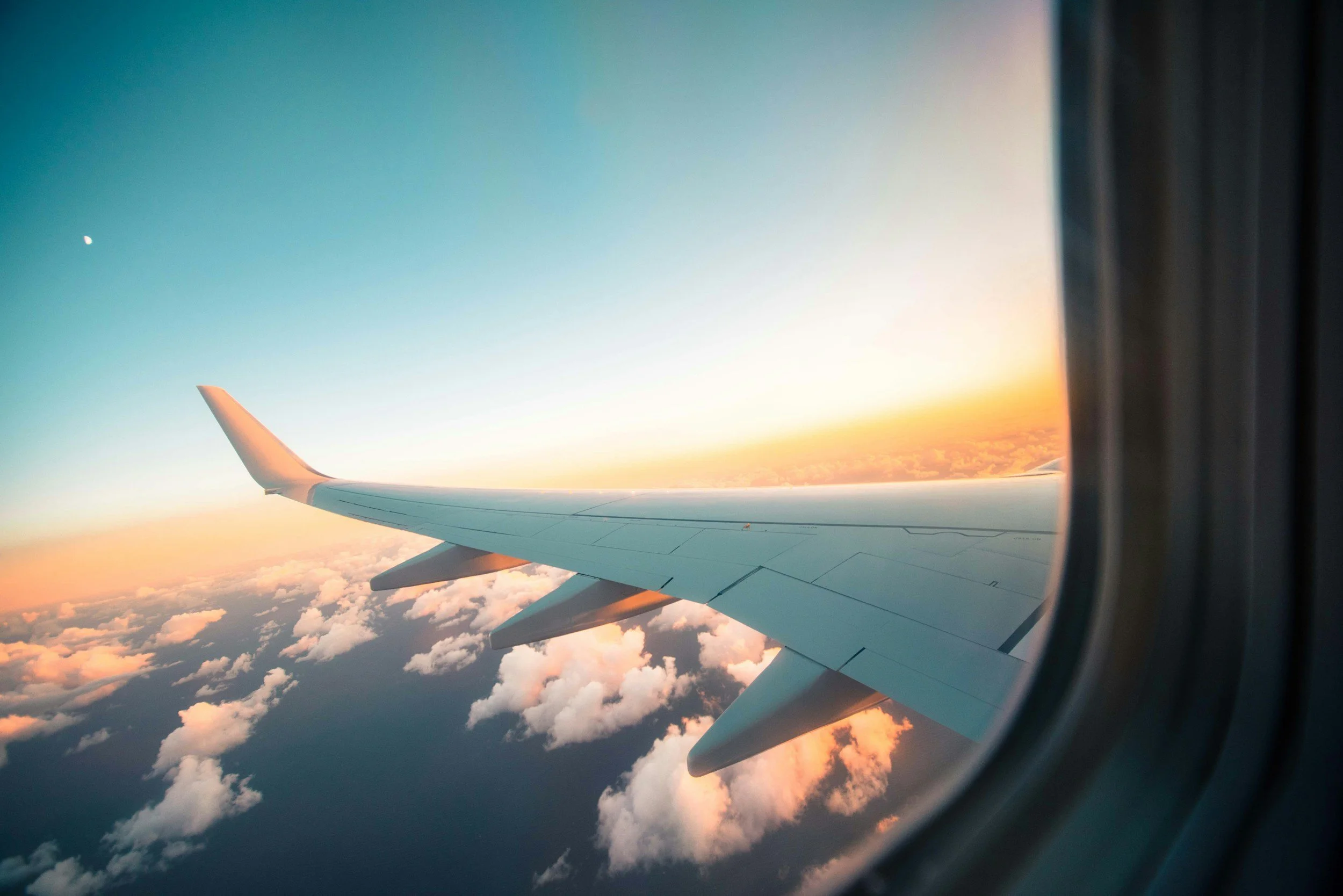 View of airplane wing against a colorful sunset sky seen from an airplane window.