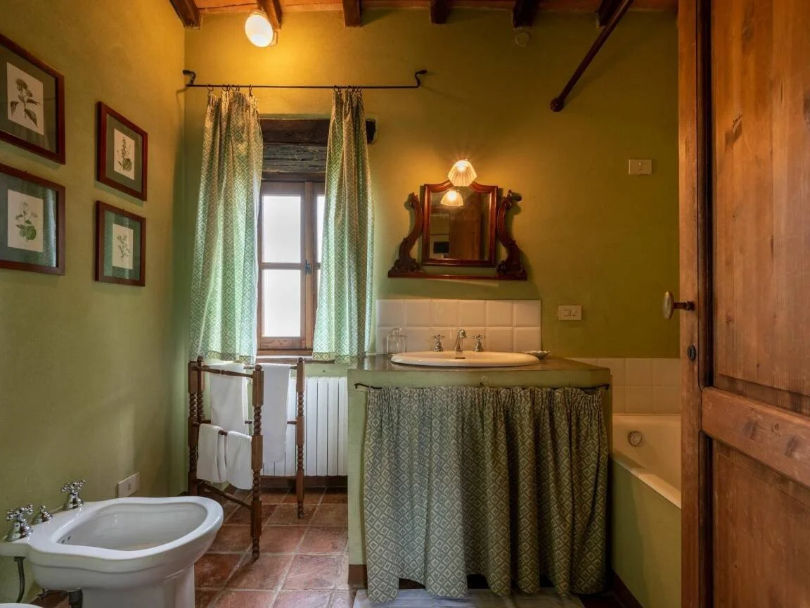A rustic bathroom with green walls and wooden accents in an italian countryside home for rent in Roccaverano near Asti, Alba, Nizza Monferrato, Aqui terme.