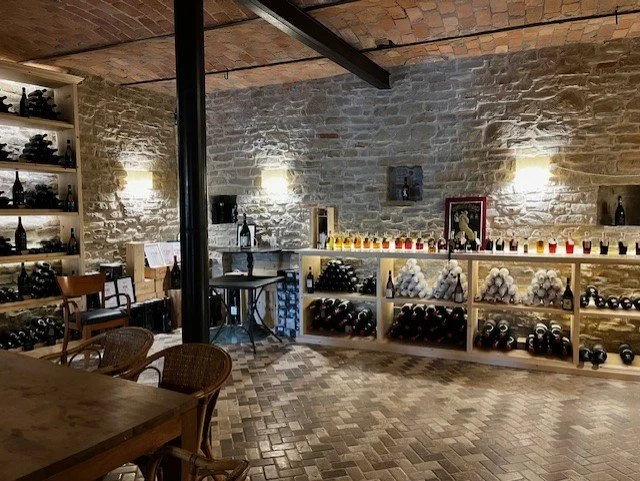 Wine cellar with stone walls, shelves of wine bottles at Isolabella della Croce, Loazolla near Roccaverano.