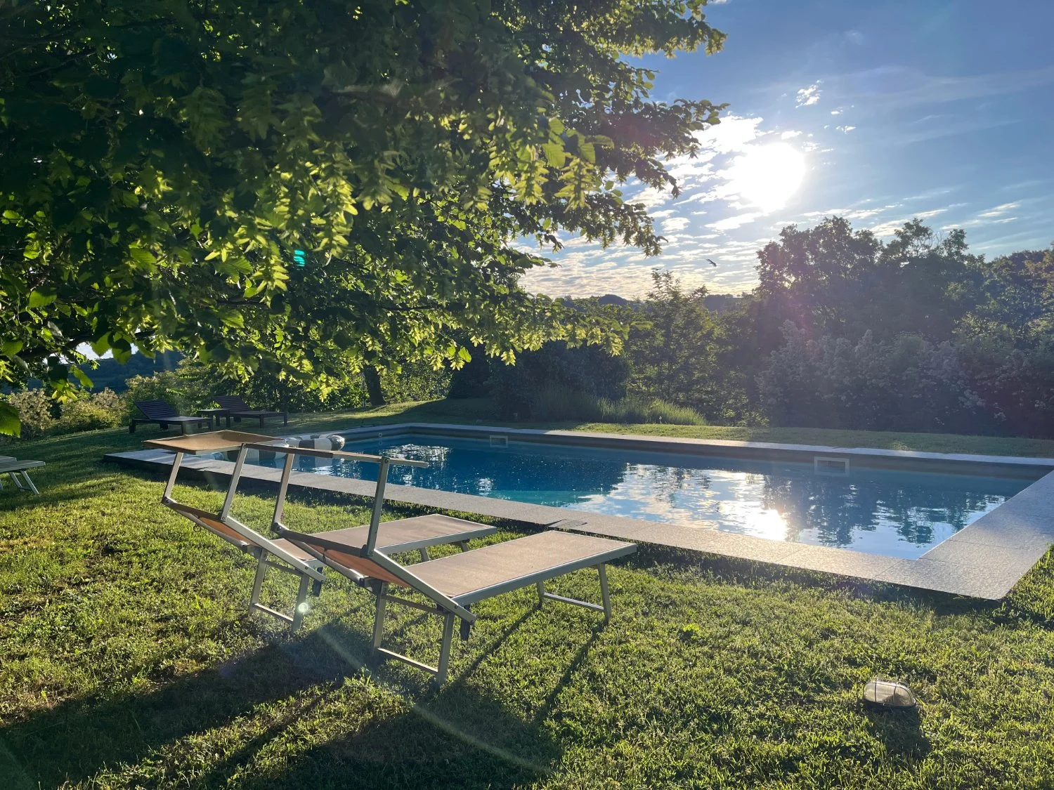 An outdoor patio of a boutique holiday rental villa with large swimming pool and garden with stunning views near Monastero Bormida.