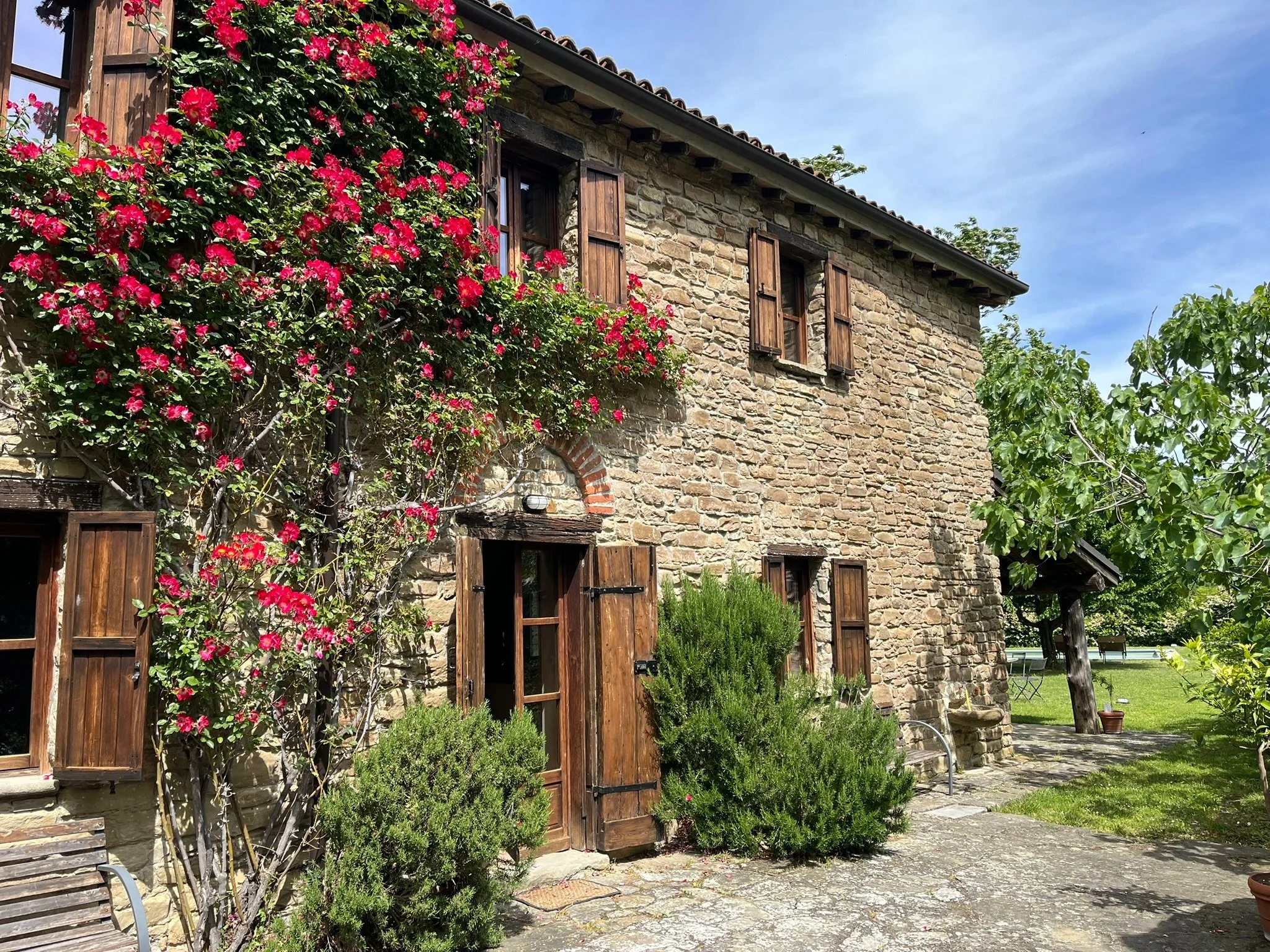 A rustic holiday house with wooden shutters and flowering climbing plants, situated between Monastero Bormida and Roccaverano.