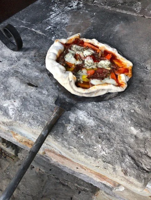 Homemade pizza ready to bake in an original italian stone pizza oven in A holiday home in Roccaverano, Piedmont. Langhe region, world unesco heritage.