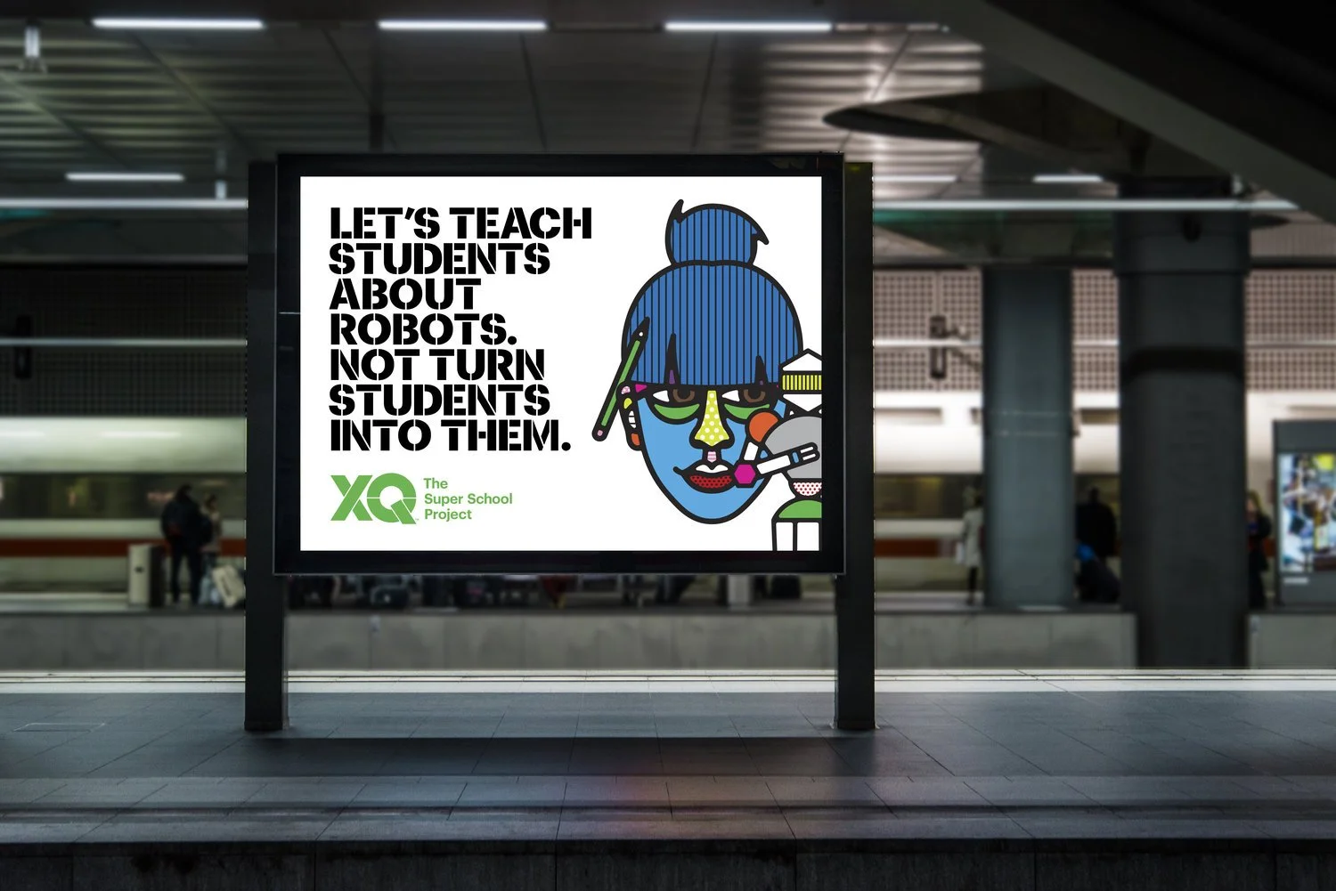 An advertisement at a train station encouraging teaching students about robots and not turning students into robots, with a colorful illustrated face of a robot girl with blue hair and various tech accessories. The text reads, "Let's teach students about robots. Not turn students into them." The logo at the bottom says "The Super School Project."