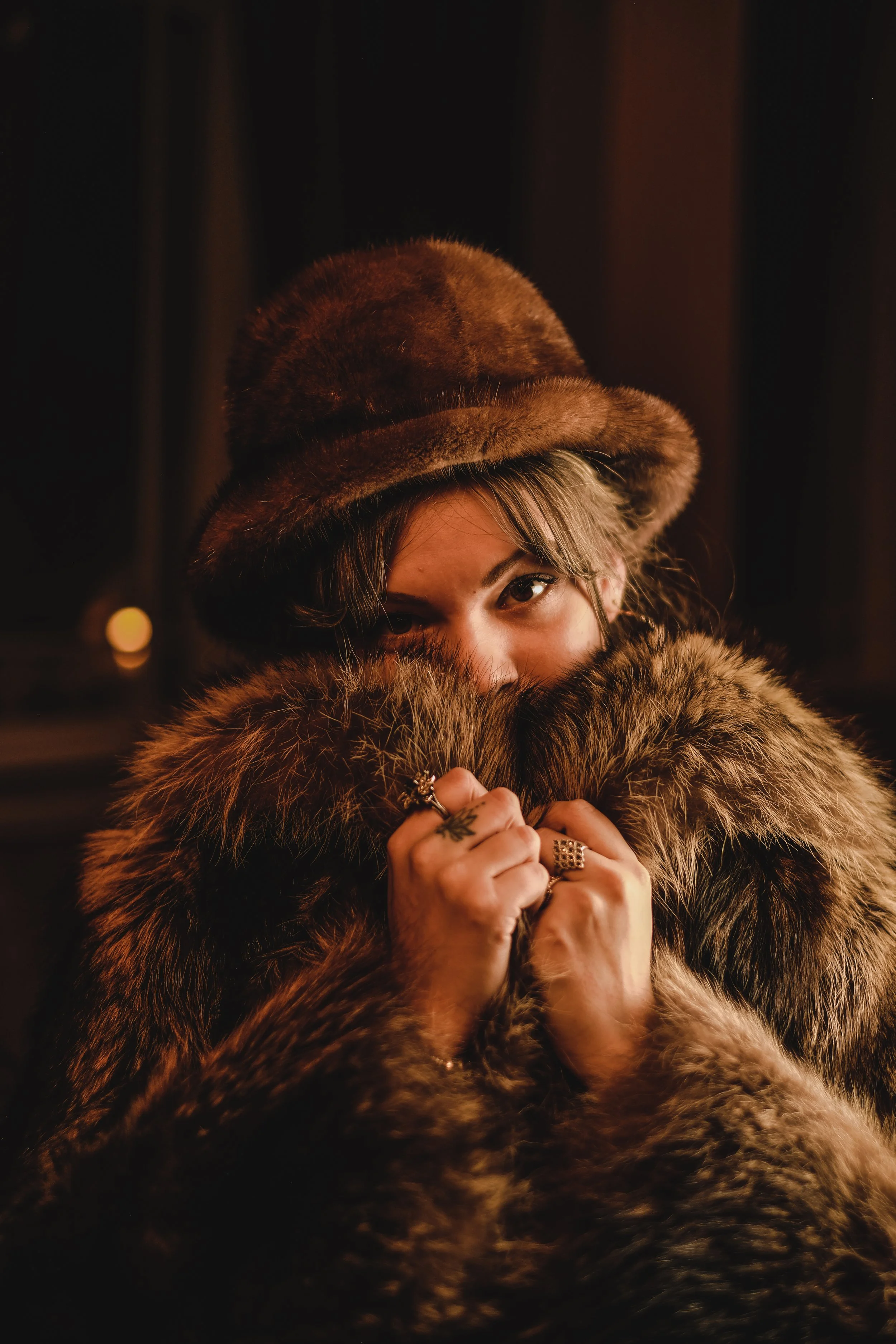 Videographer in Montreal capturing professional music videos, corporate videos, and live events. High-qualityA woman with blonde hair wearing a brown fur hat and a matching fur coat, covering part of her face with her hands and looking at the camera.