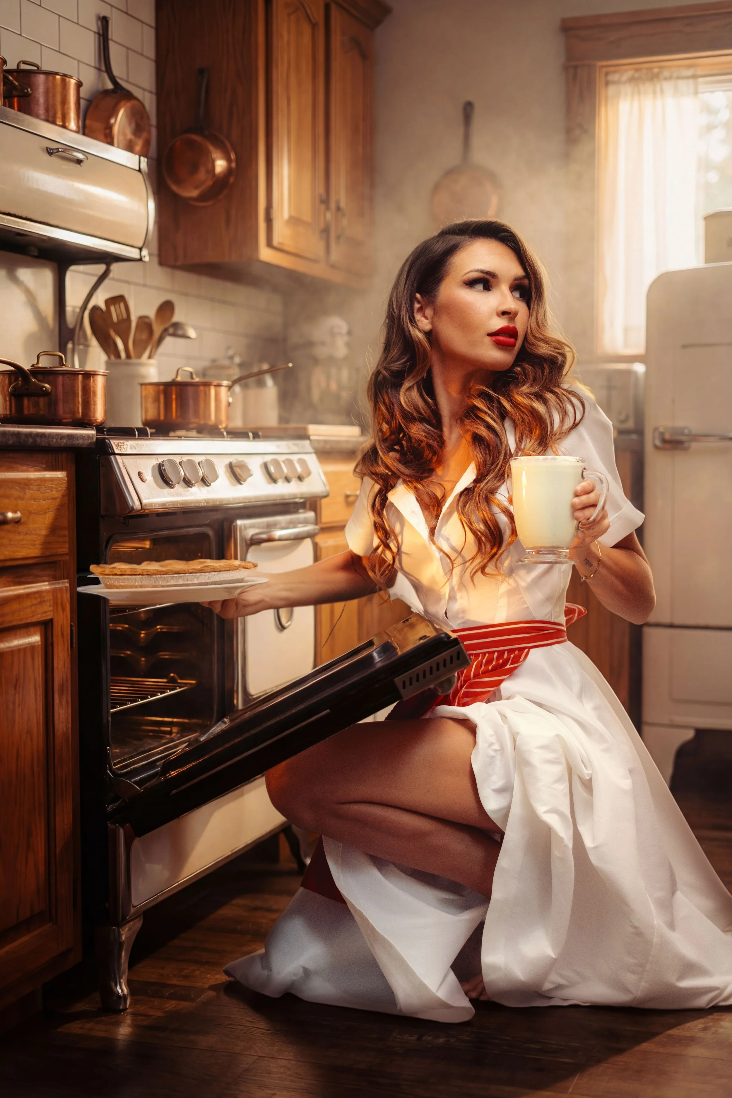 A woman with long wavy hair, wearing a vintage white dress with red accents, kneeling in a retro-style kitchen. She holds a plate with baked goods in one hand and a mug in the other, with an oven door open.