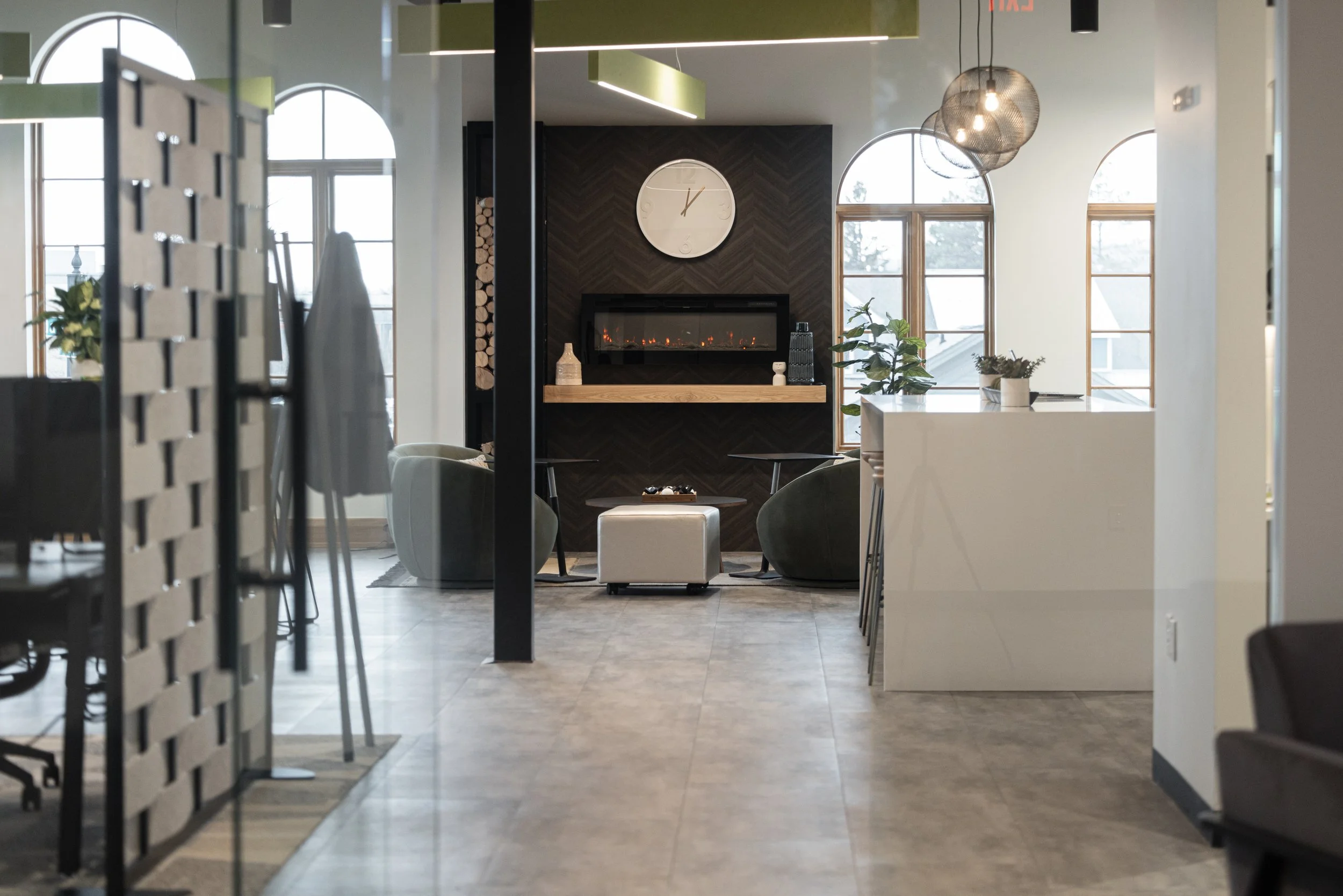 Interior of a modern lounge area with large arched windows, a fireplace, and contemporary furniture.