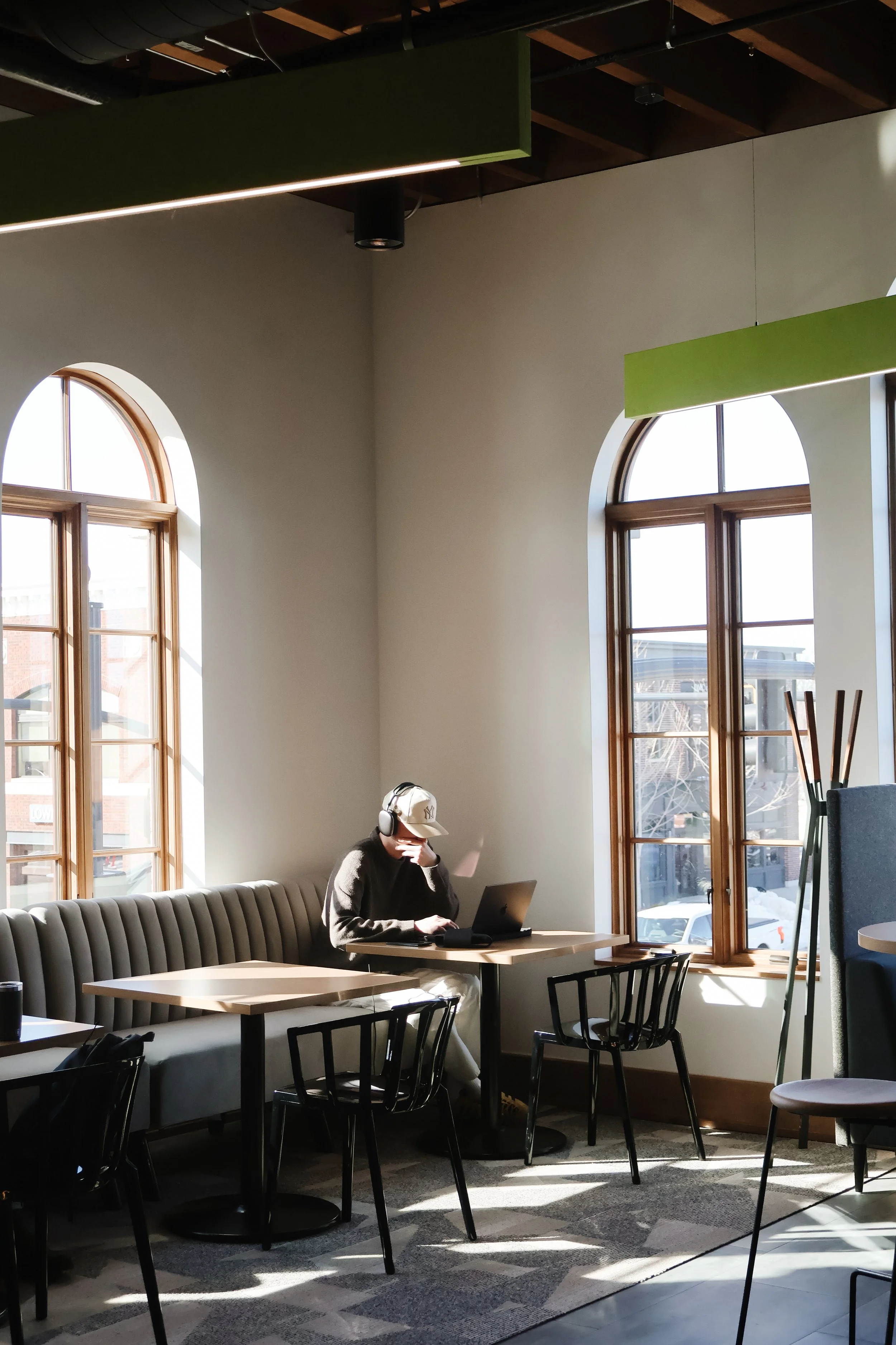 A smiling man with glasses and a beard, wearing a tan sweater, sitting at a conference table during a meeting.