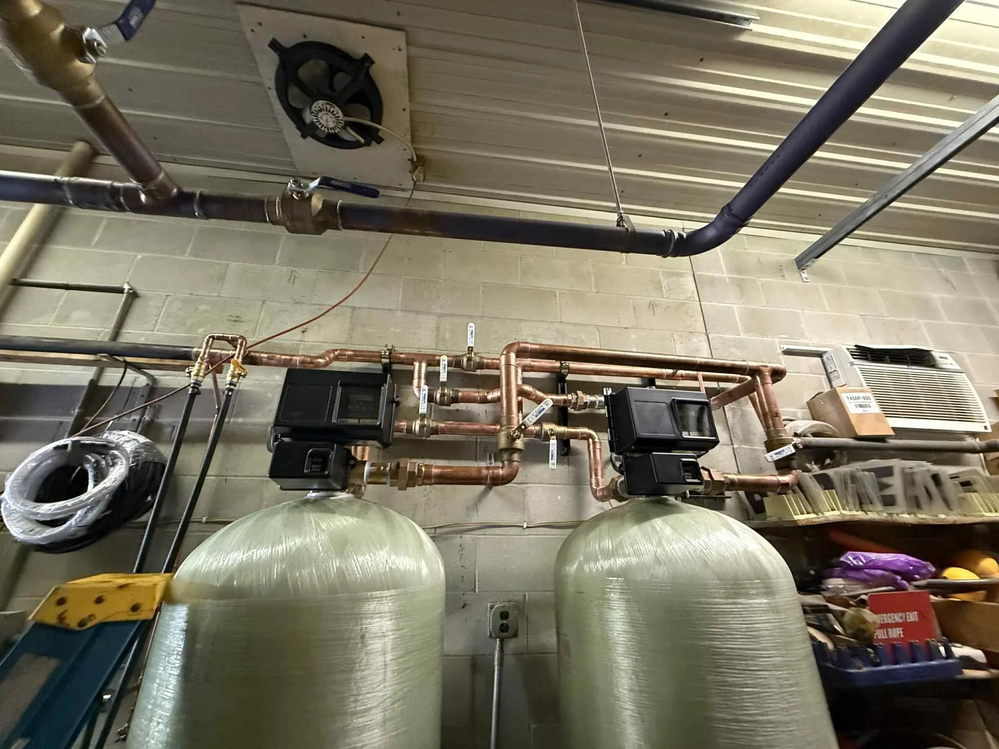 Industrial water treatment system with large green tanks and copper piping.