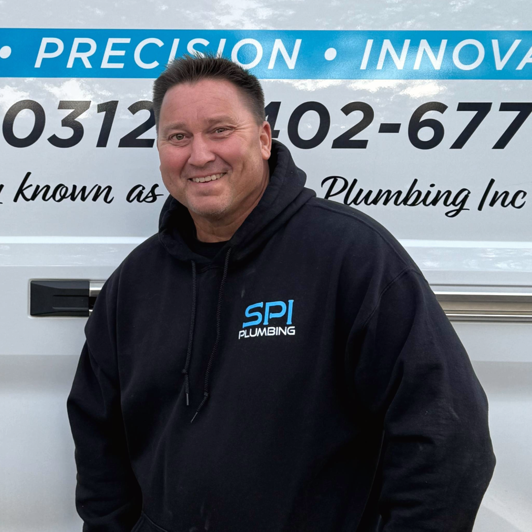 Man smiling in front of a plumbing van wearing a black hoodie with SPI Plumbing logo.