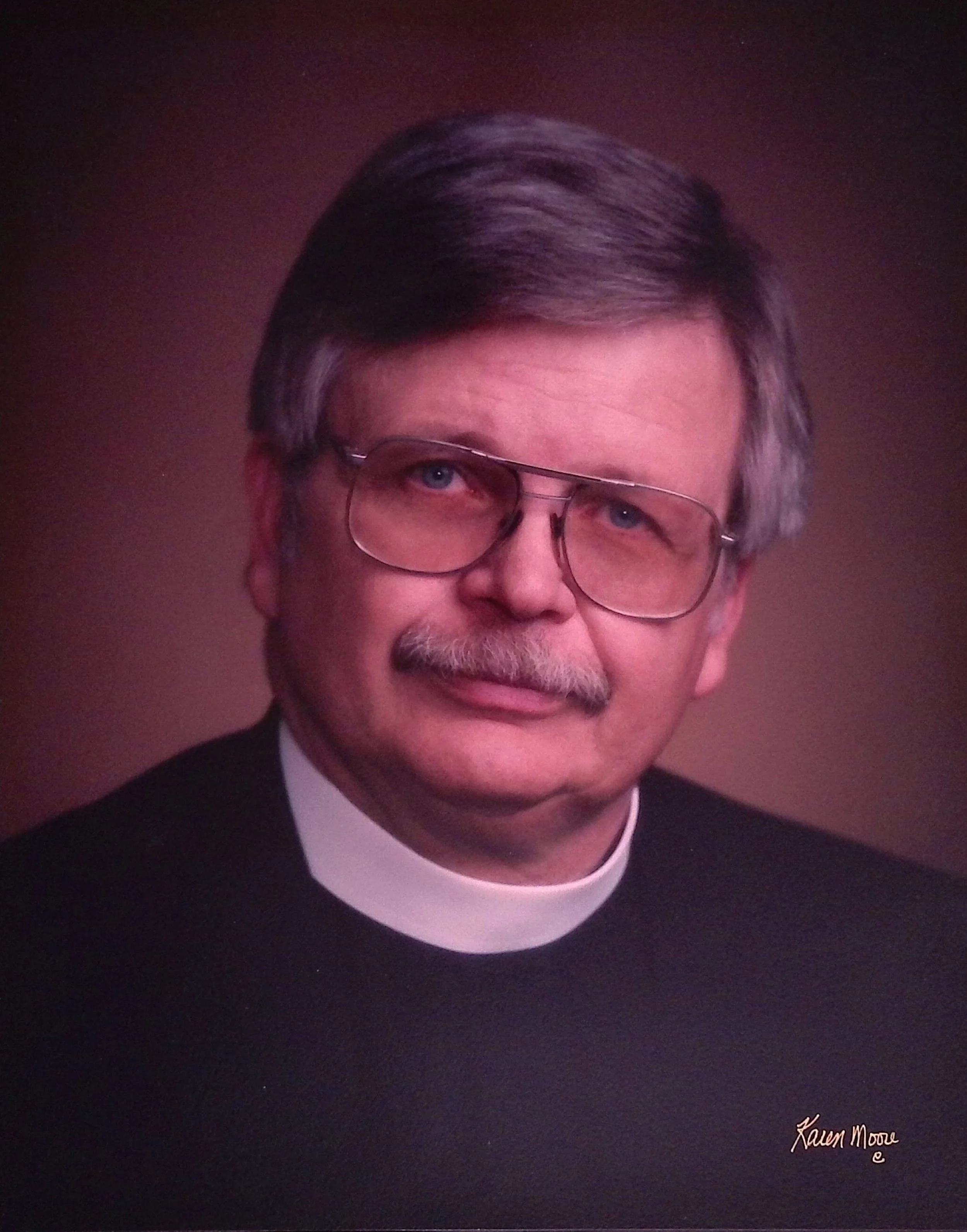 Black and white portrait of an older man with grey hair, glasses, and a mustache.
