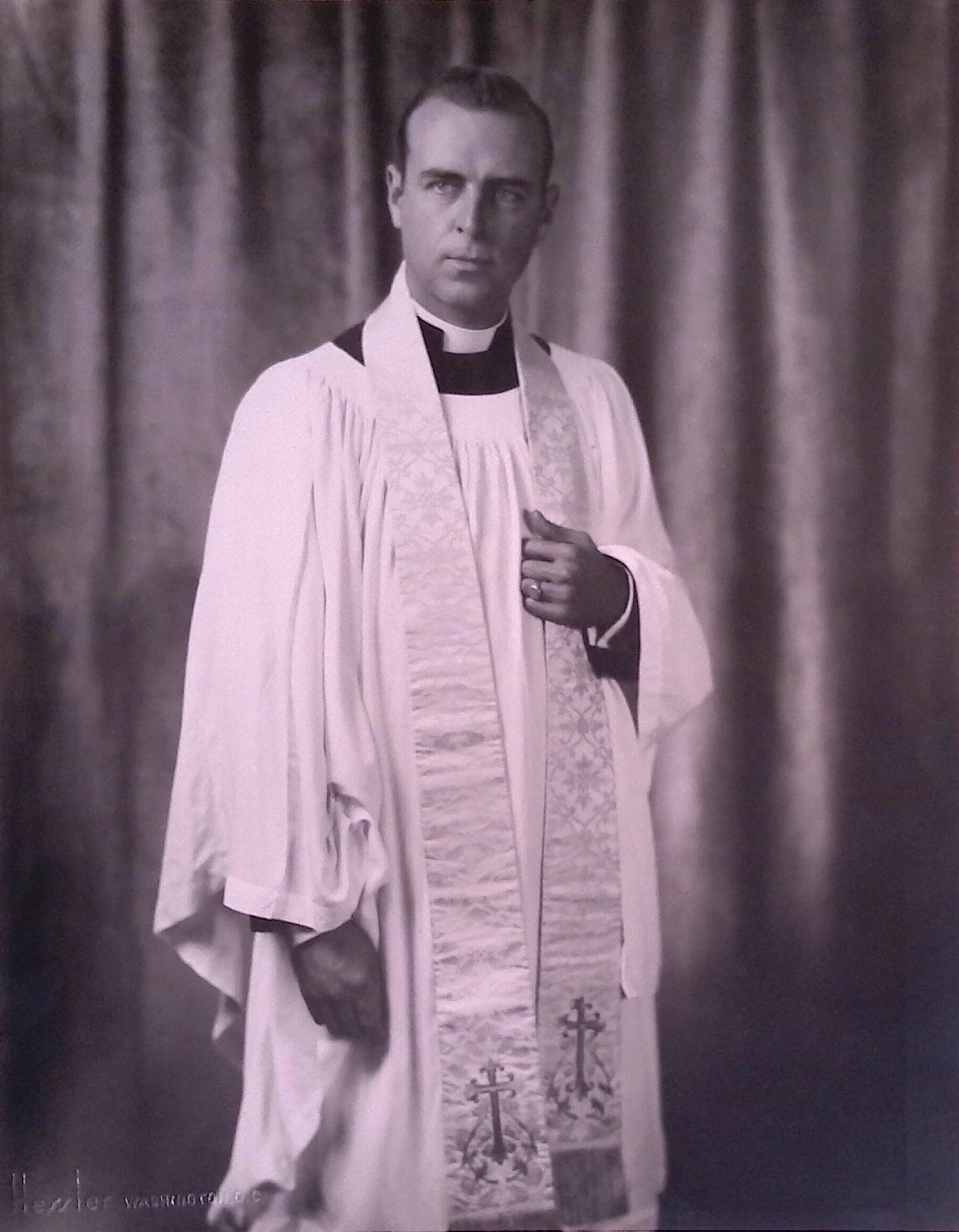 A black-and-white portrait of a young man with short hair, dressed in clerical attire, likely a priest.