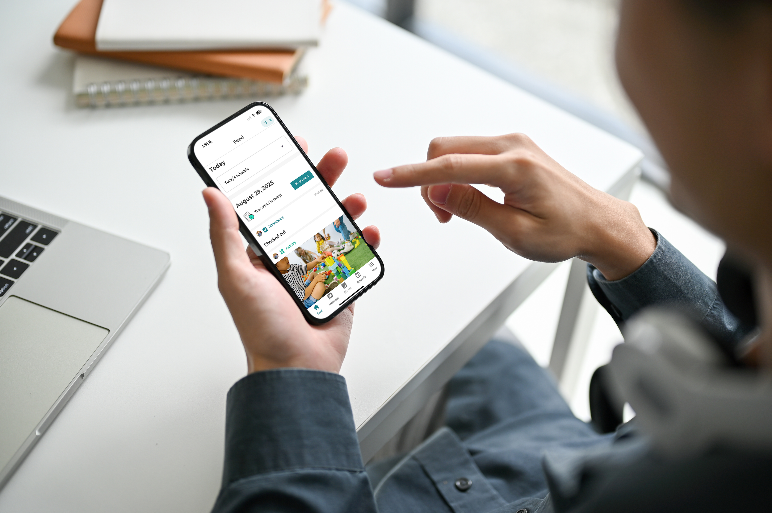 Person holding a smartphone showing a scheduling app with a photo of children playing with toys.
