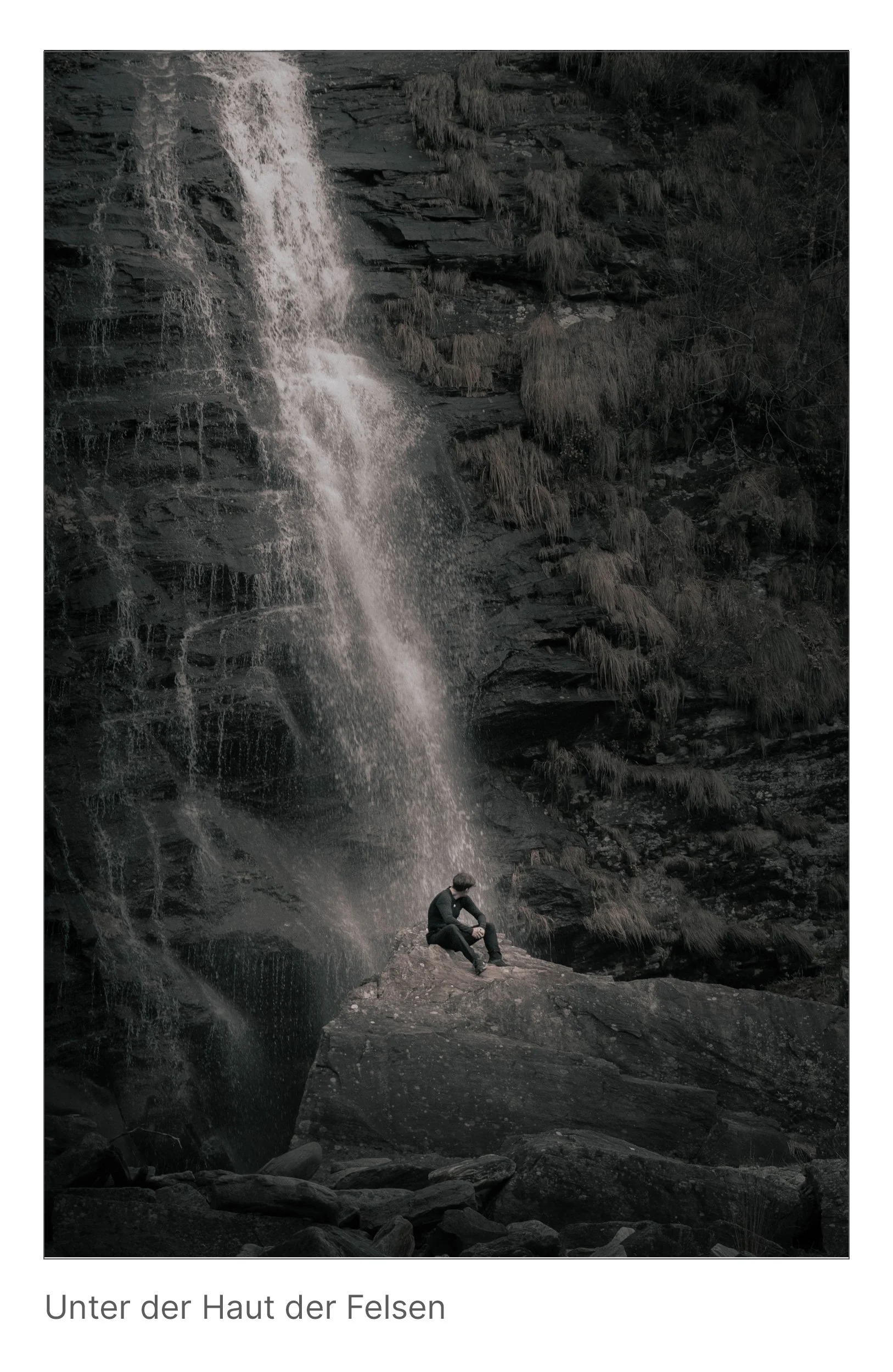 Wasserfall trifft auf Felswand, Mensch sitzt darunter im Licht – Begegnung zwischen Naturgewalt und innerer Stille.