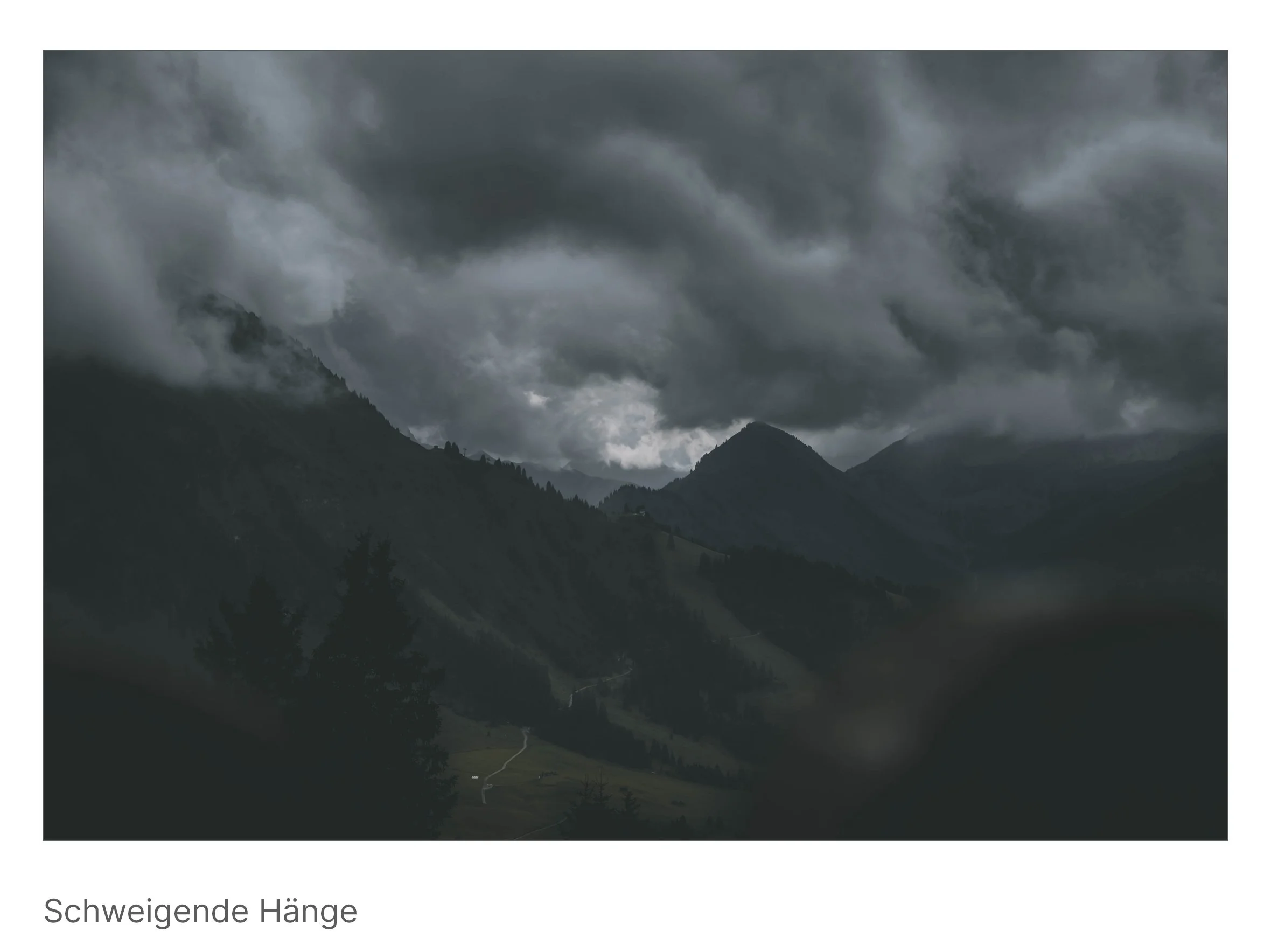 Dunkle Bergsilhouetten unter schwerem Himmel, Wolken berühren die Gipfel – ein Moment voll Ruhe und innerem Gewicht.