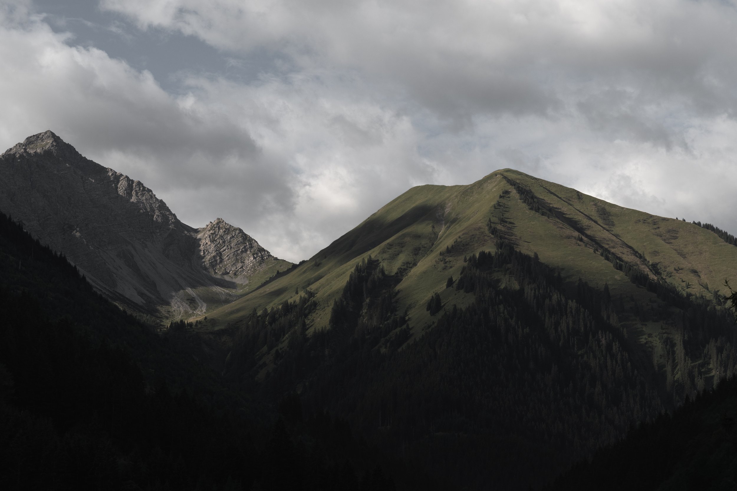 Alpenlandschaft im Wechsellicht
Grüne Berghänge und felsige Gipfel unter dramatischem Wolkenhimmel und wechselndem Licht – Landschaftsfotografie von ReBlick.