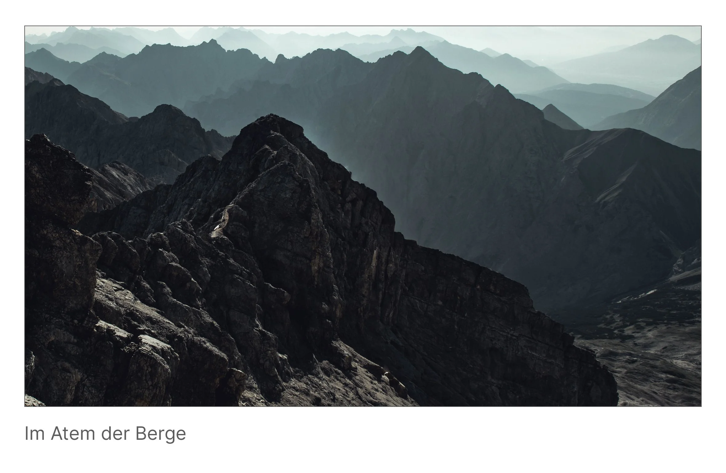 Panorama aus gestaffelten Gebirgssilhouetten im Morgenlicht, weiche Nebelschichten füllen die Täler – Darstellung von Tiefe, Ruhe und Weite.