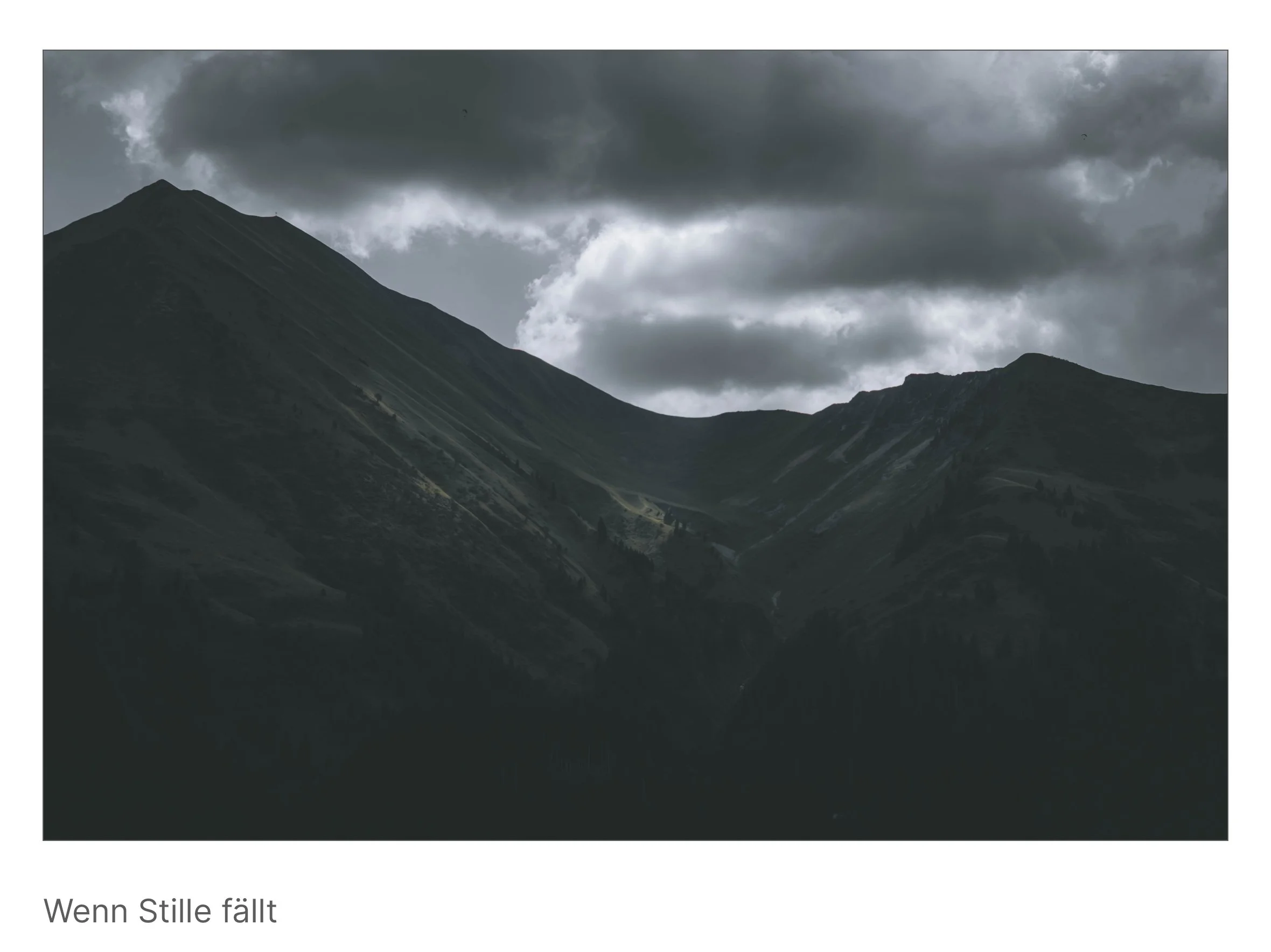 Zwei Berggipfel unter dunklen Wolken, das Licht bricht kaum hindurch – Moment, in dem die Landschaft den Atem anhält.