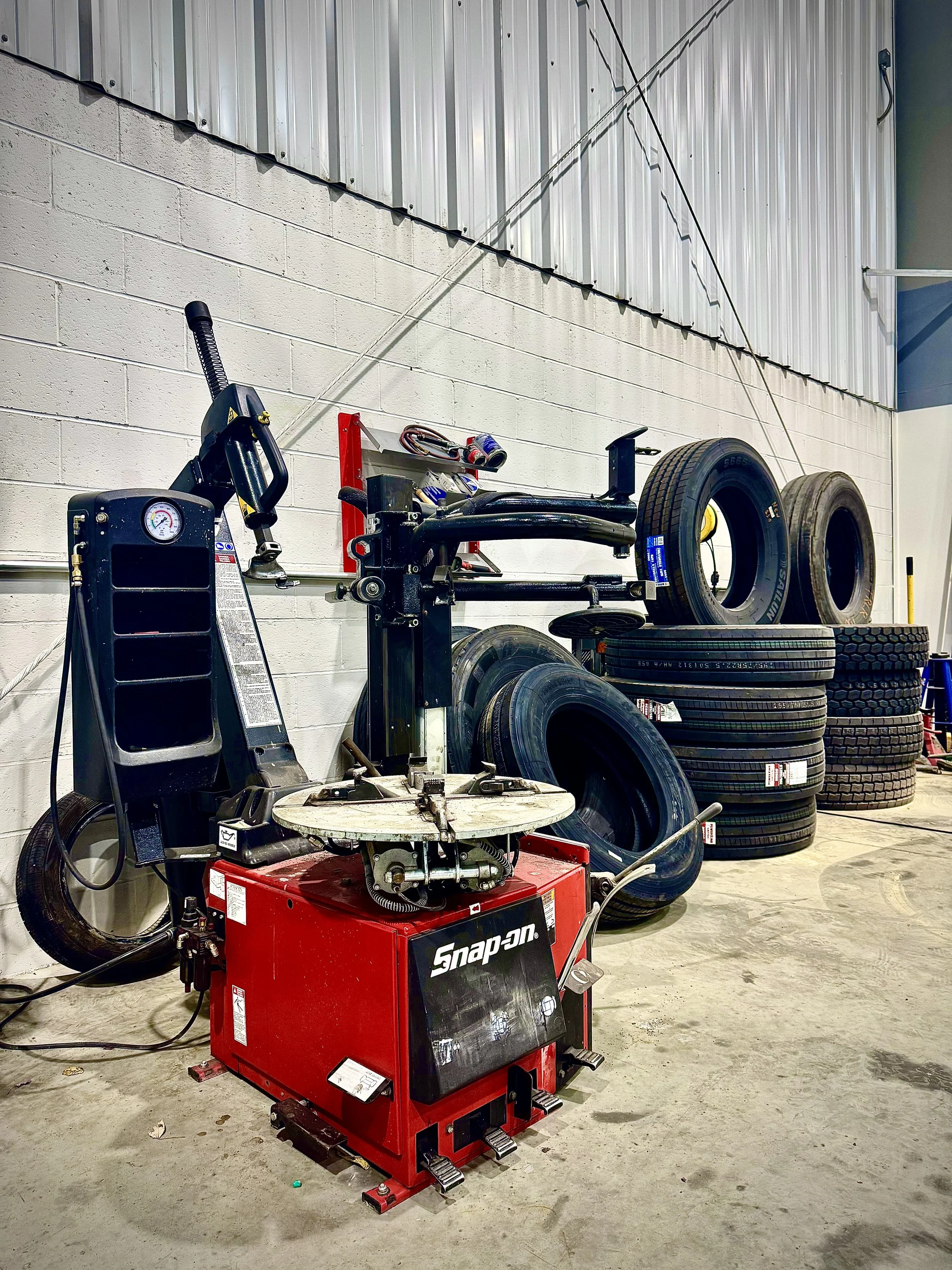 PRS Truck Repair tire mounting machine and stack of heavy-duty truck tires inside the Burgettstown, PA service facility