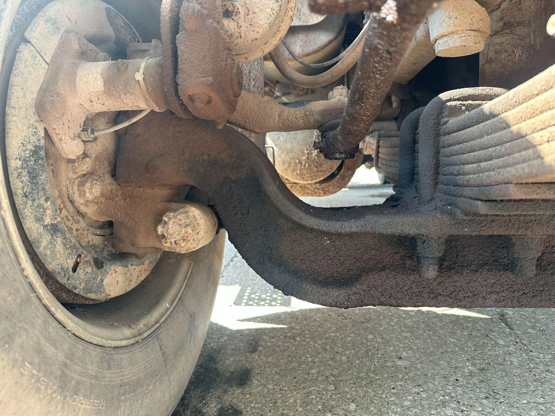 Close-up of a rusty truck or vehicle chassis with visible suspension components and a large tire.