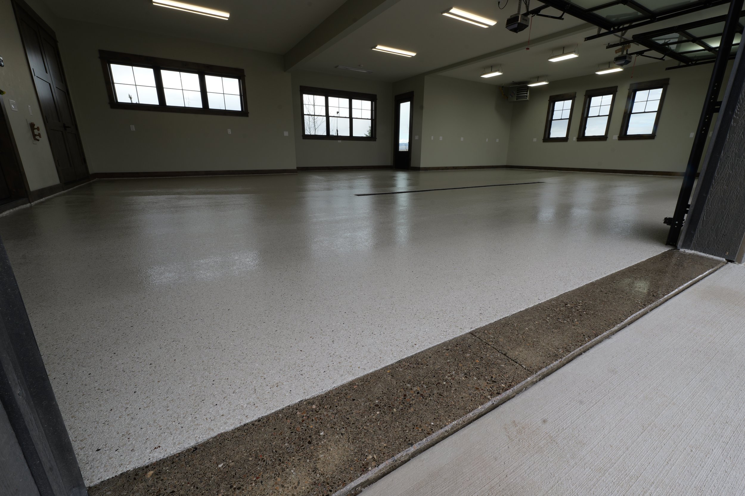 Empty indoor gym or community room with large windows, polished floor, and ceiling lights.