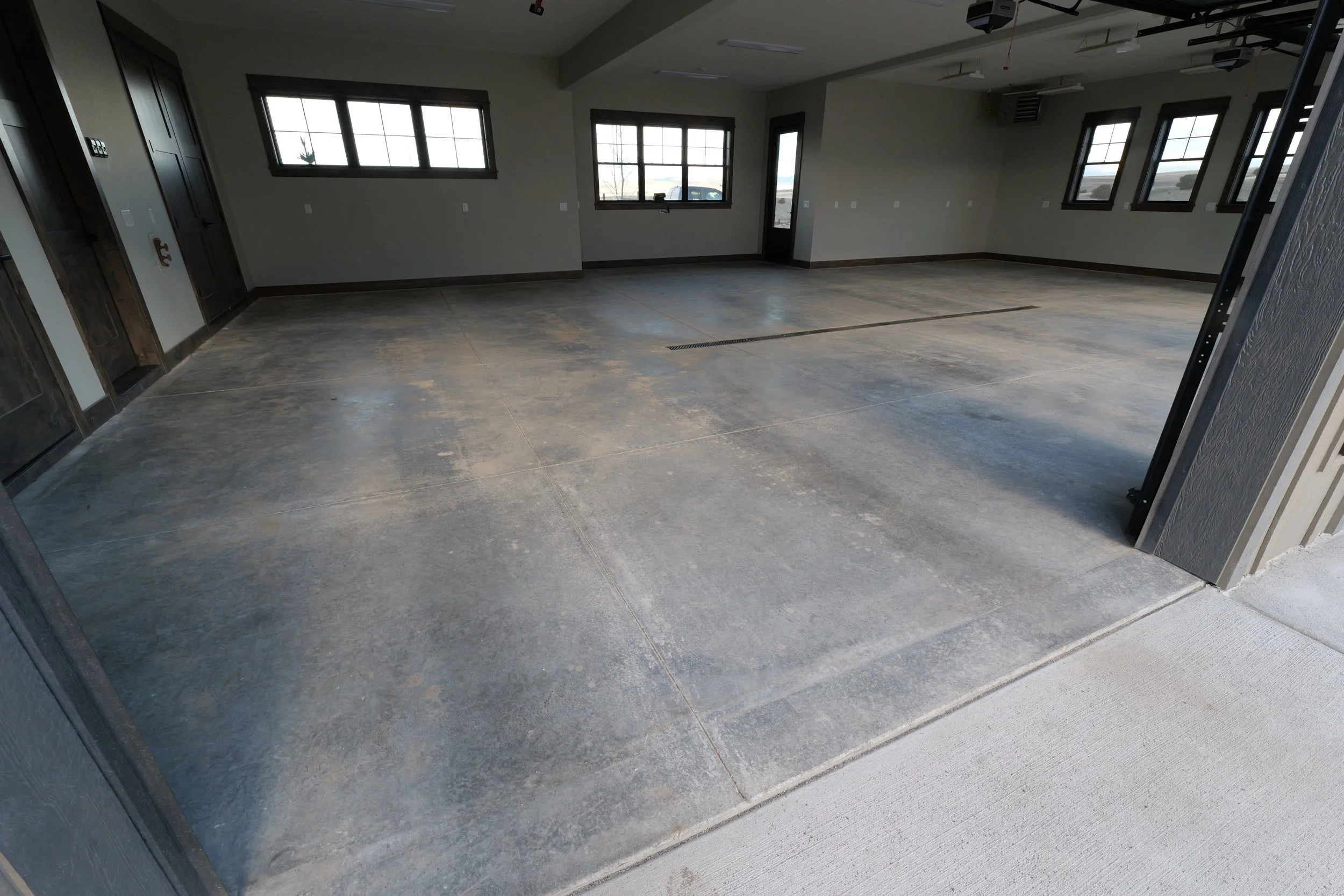 Empty room with concrete flooring, several windows providing natural light, and no furniture.