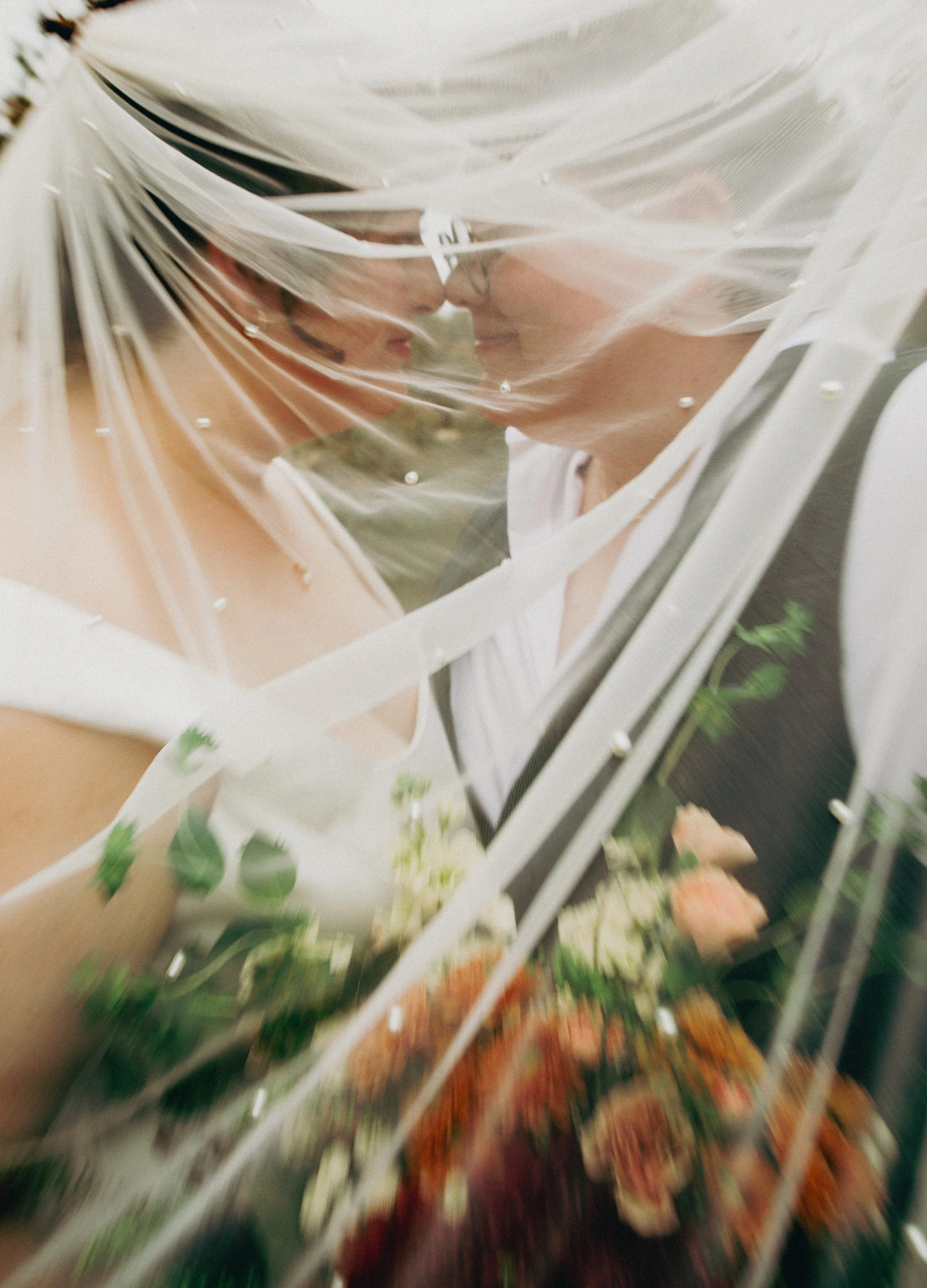 A person wearing glasses and a white shirt is behind a floral-patterned metal gate or fence, with a blurred background.