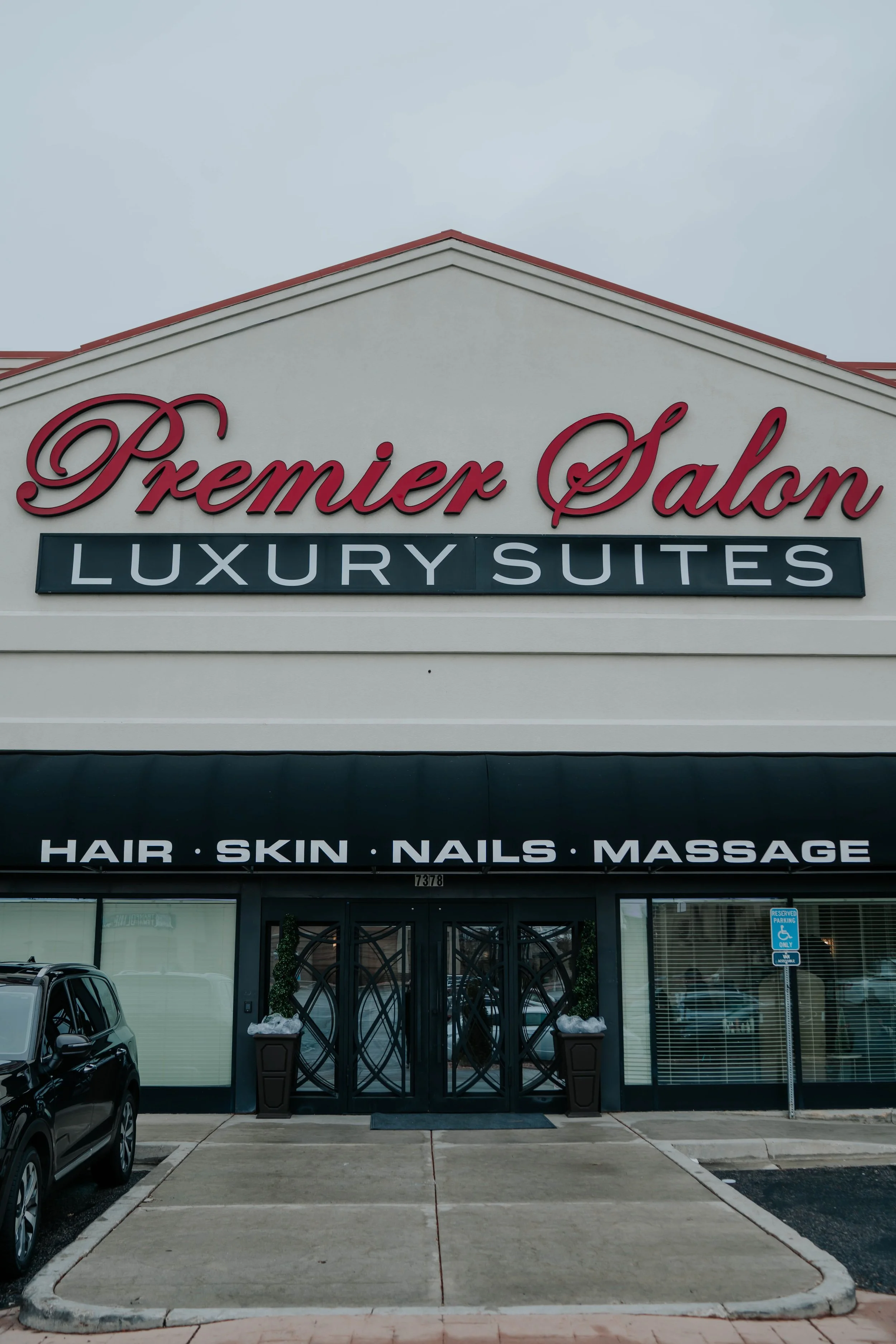 Exterior view of a salon building with signage indicating it offers hair, skin, nails, and massage services, and features a sign for luxury suites.