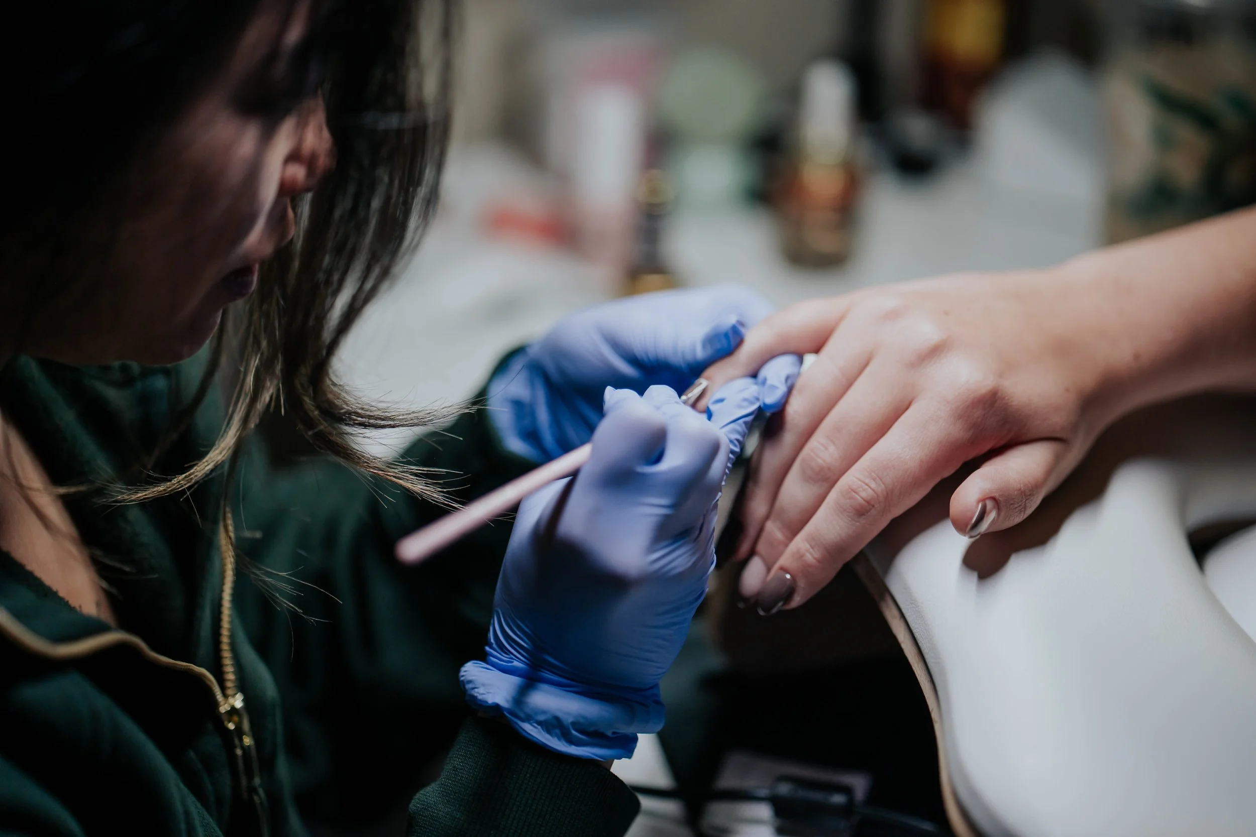 A person getting a tattoo on their hand from a tattoo artist wearing blue gloves.