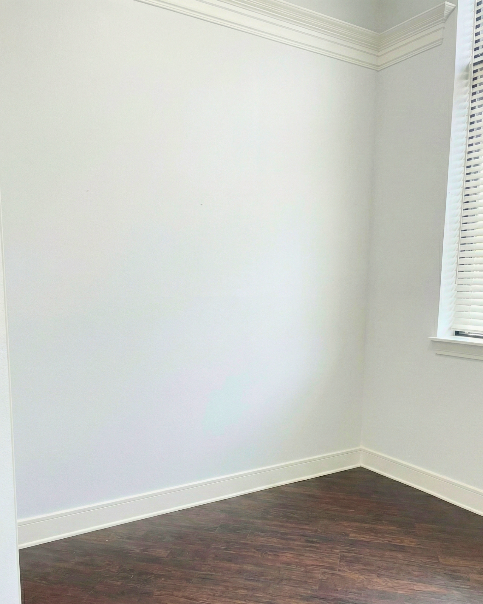 Empty white room with a window and wood floor.