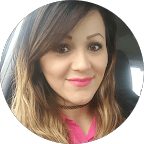 Close-up of a woman with shoulder-length brown hair, smiling, wearing a pink top and black choker