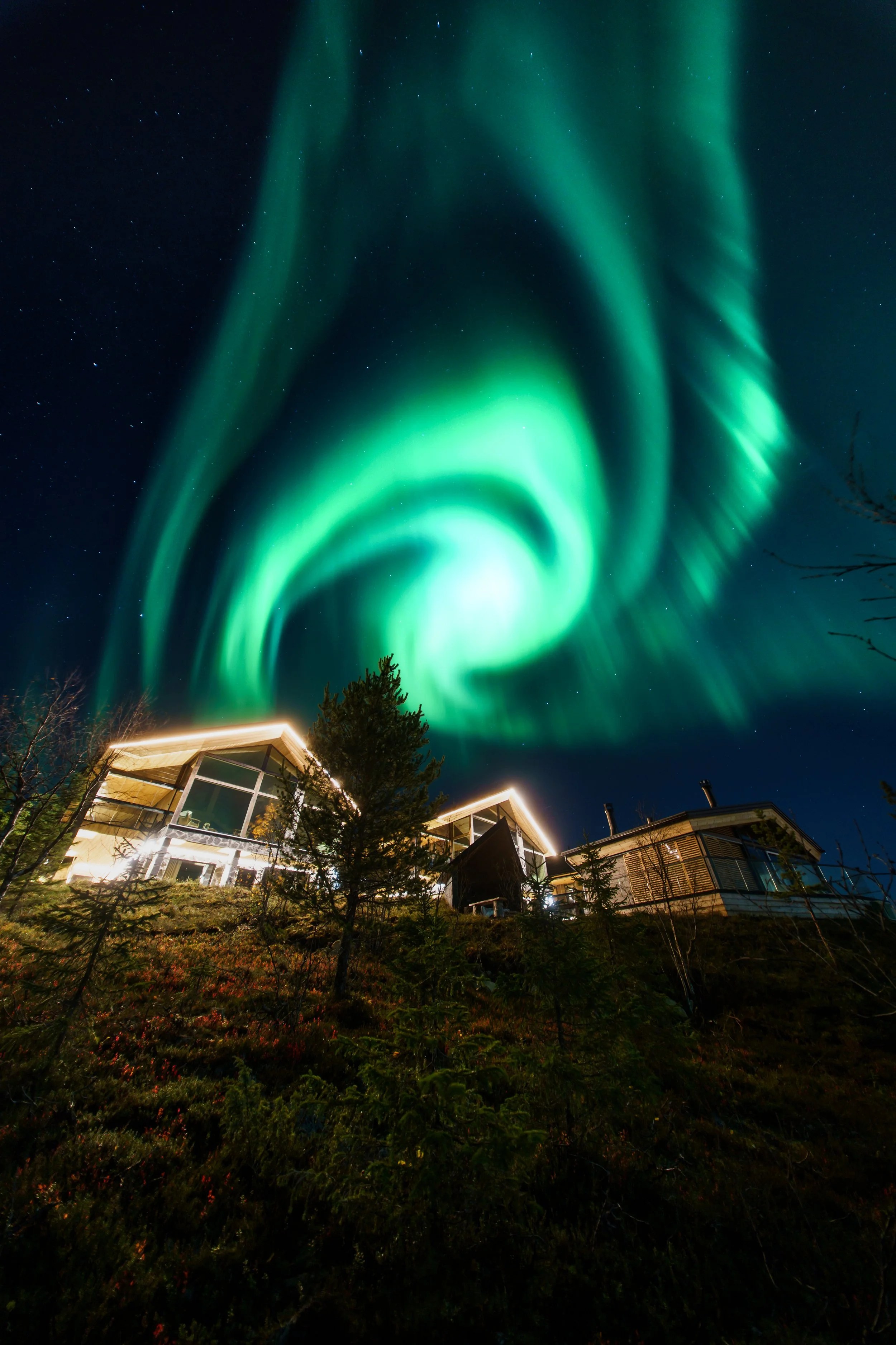 Northern lights (Aurora Borealis) glowing green in the night sky in Ylläs above Kide Lodges.