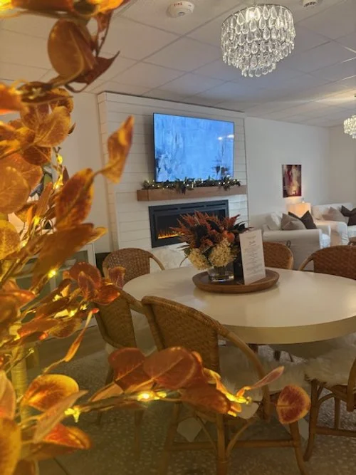 Decorative table with a flower arrangement in a cozy interior living room with a fireplace, chandelier, and TV.