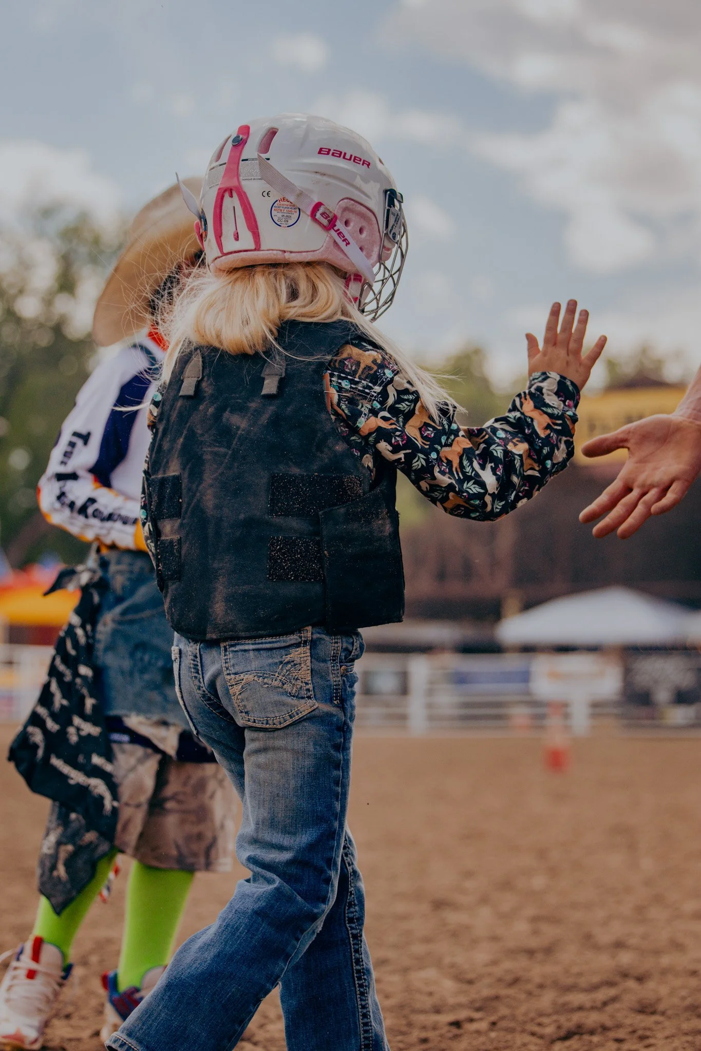A young girl giving high fives after her mutton busting ride.