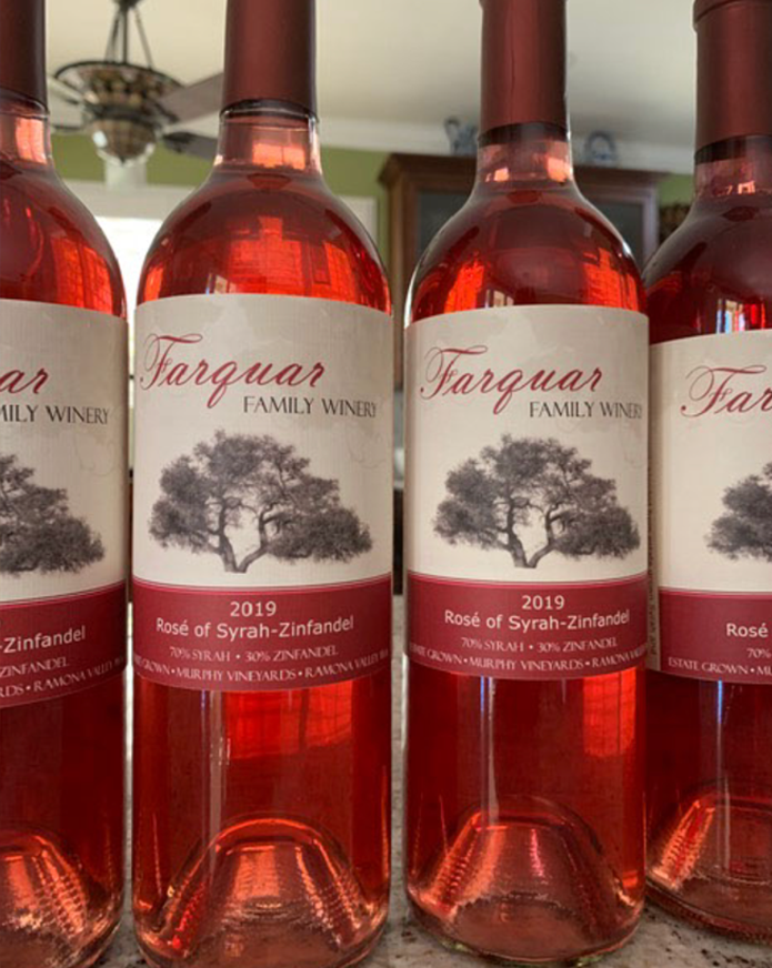 Four bottles of rosé wine from Farquar Family Winery, 2019, with a label featuring a large tree, on a kitchen counter.