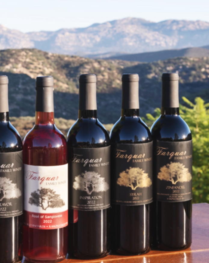 Five bottles of Farquar Family Wine are lined up on a table with Ramona in the background, rose and red wines.