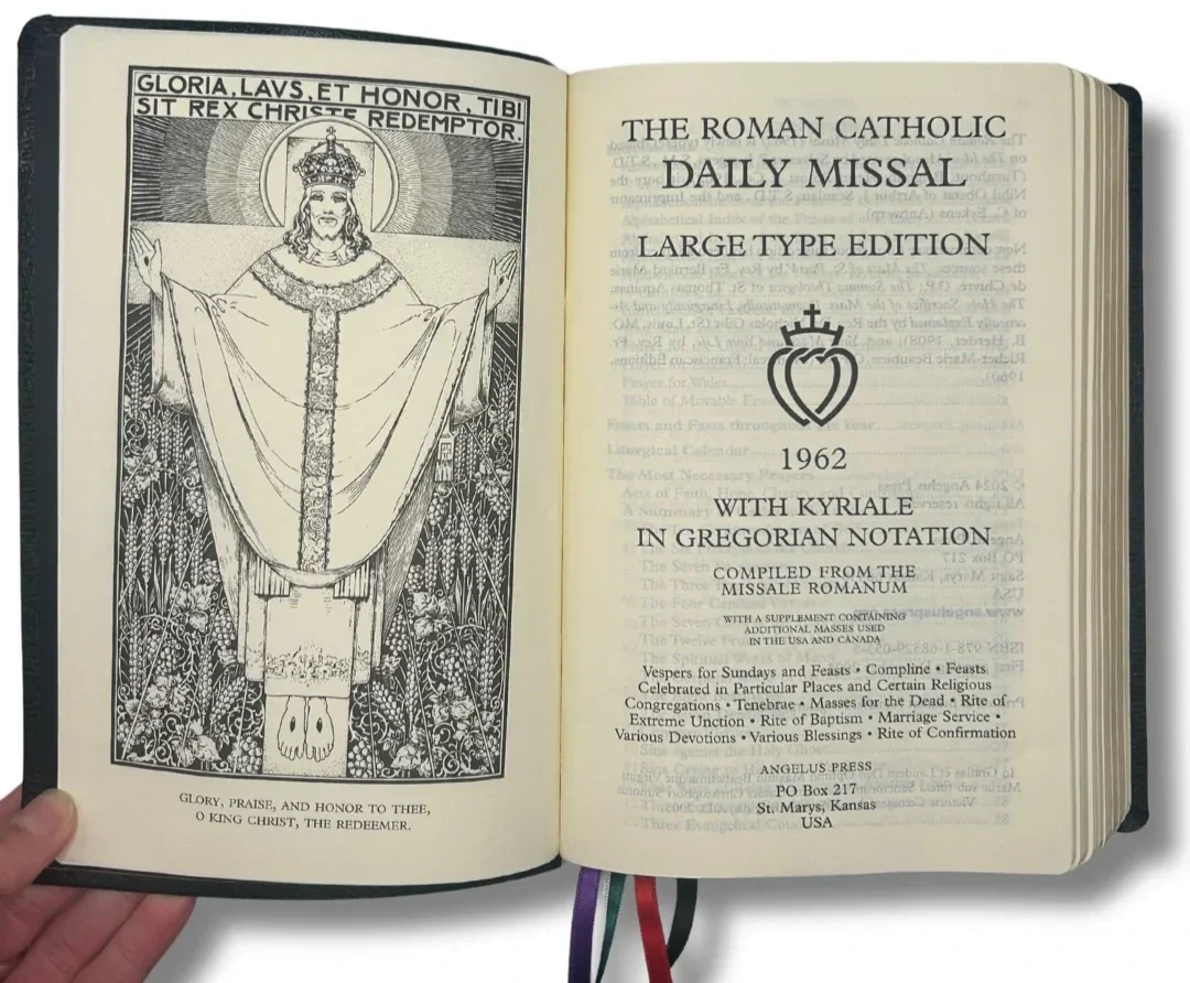 Open book titled "The Roman Catholic Daily Missal Large Type Edition 1962" with Kyriale in Gregorian notation. Contains a black and white illustration of Christ with outstretched arms on the left page.