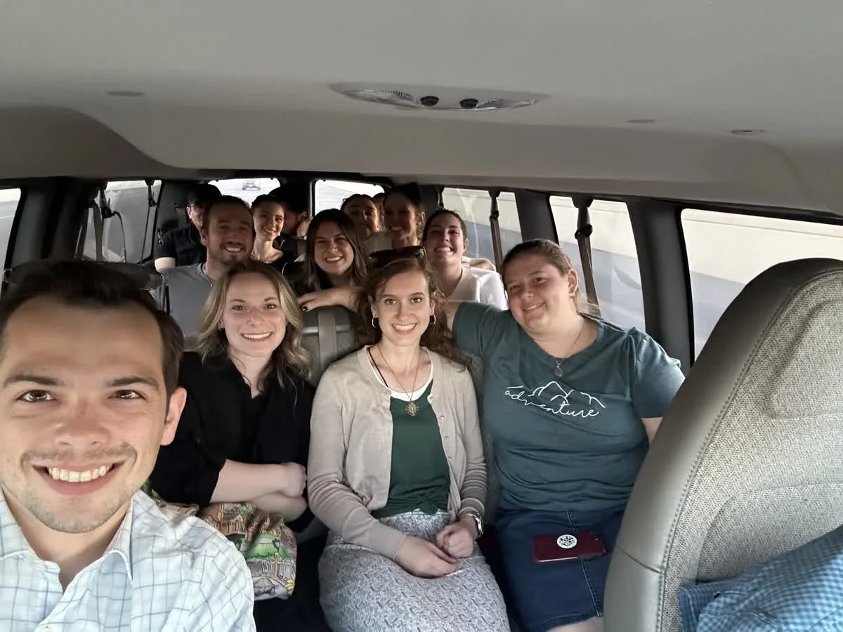 Group of smiling people inside a van, taking a selfie.