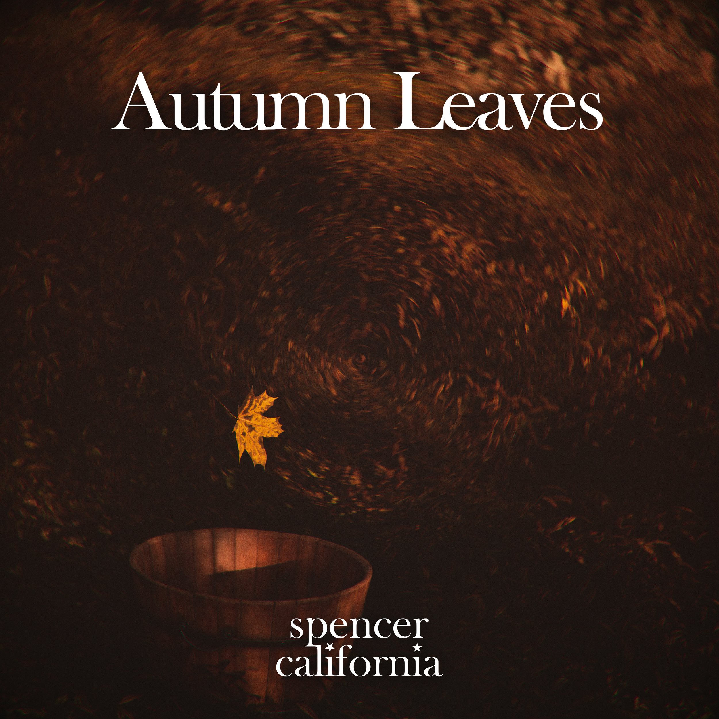 A cover of an album titled 'Autumn Leaves' by Spencer California, featuring a swirling pattern of autumn leaves in shades of orange and brown with a single leaf floating above a wooden container.