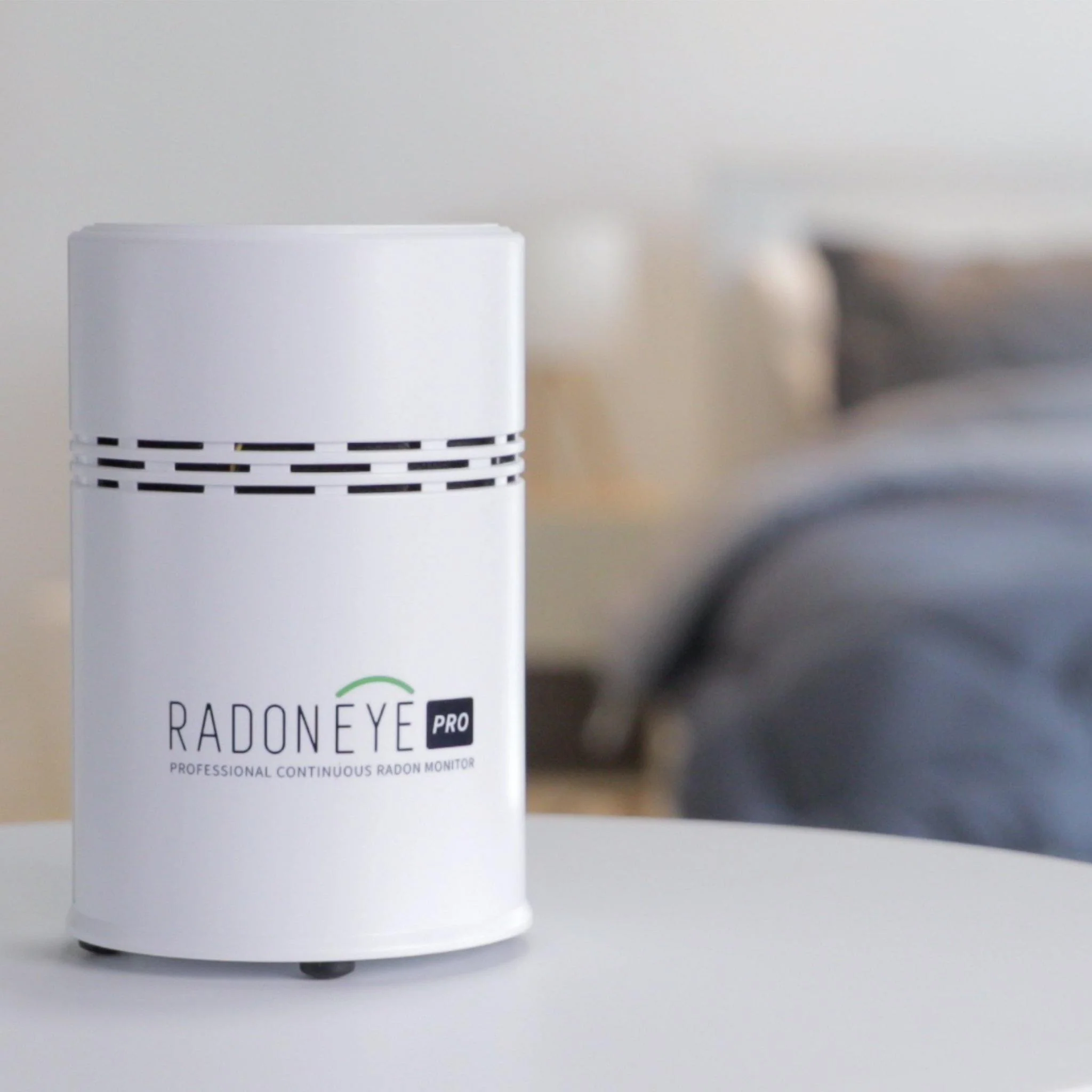 A white Radon Eye Pro device on a white surface with a blurred background.
