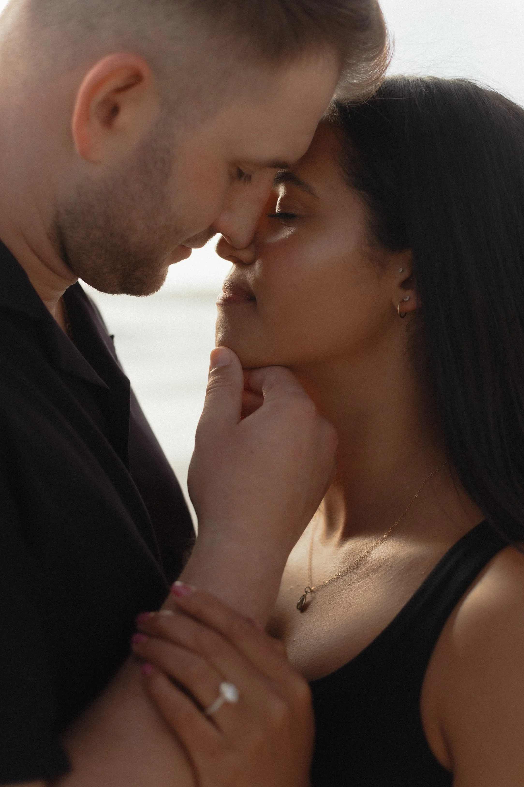 A close-up of a loving man and woman touching foreheads with eyes closed outdoors.