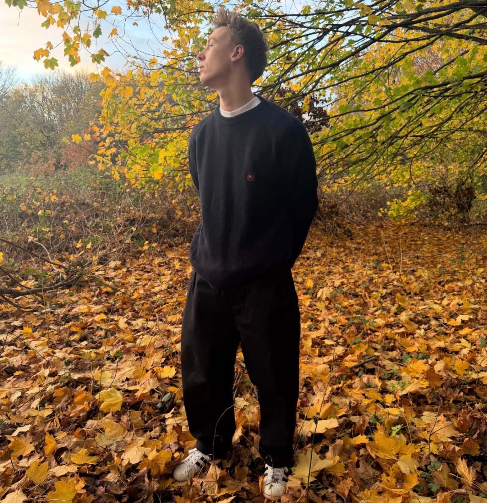 Model wearing a navy herringbone Chaps crewneck sweater styled in autumn foliage for the Foundry Archives AW25 release.