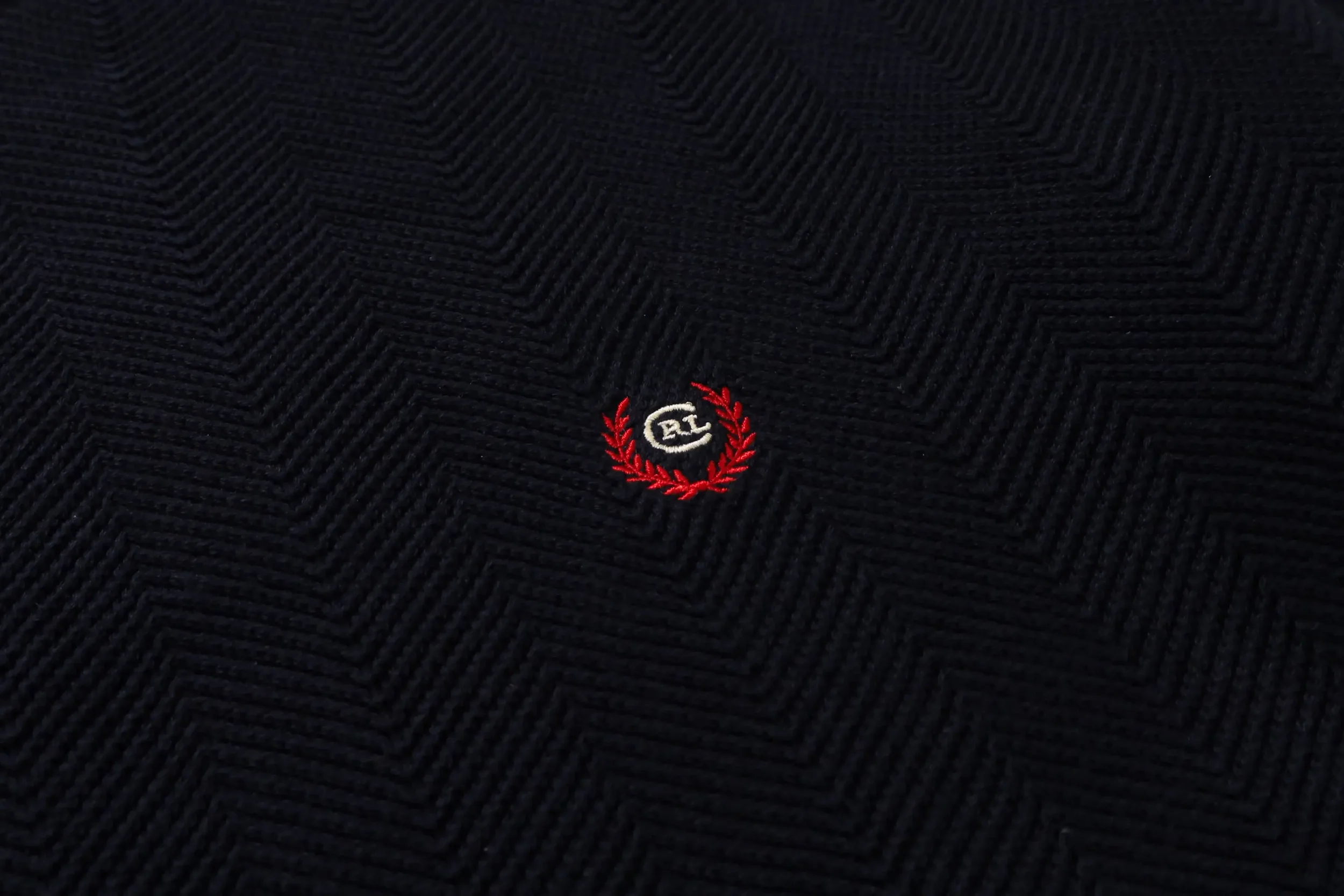 Close-up of a vintage Navy Herringbone textured sweater with a low-key minimal embroidered Ralph Lauren chaps logo in the center.