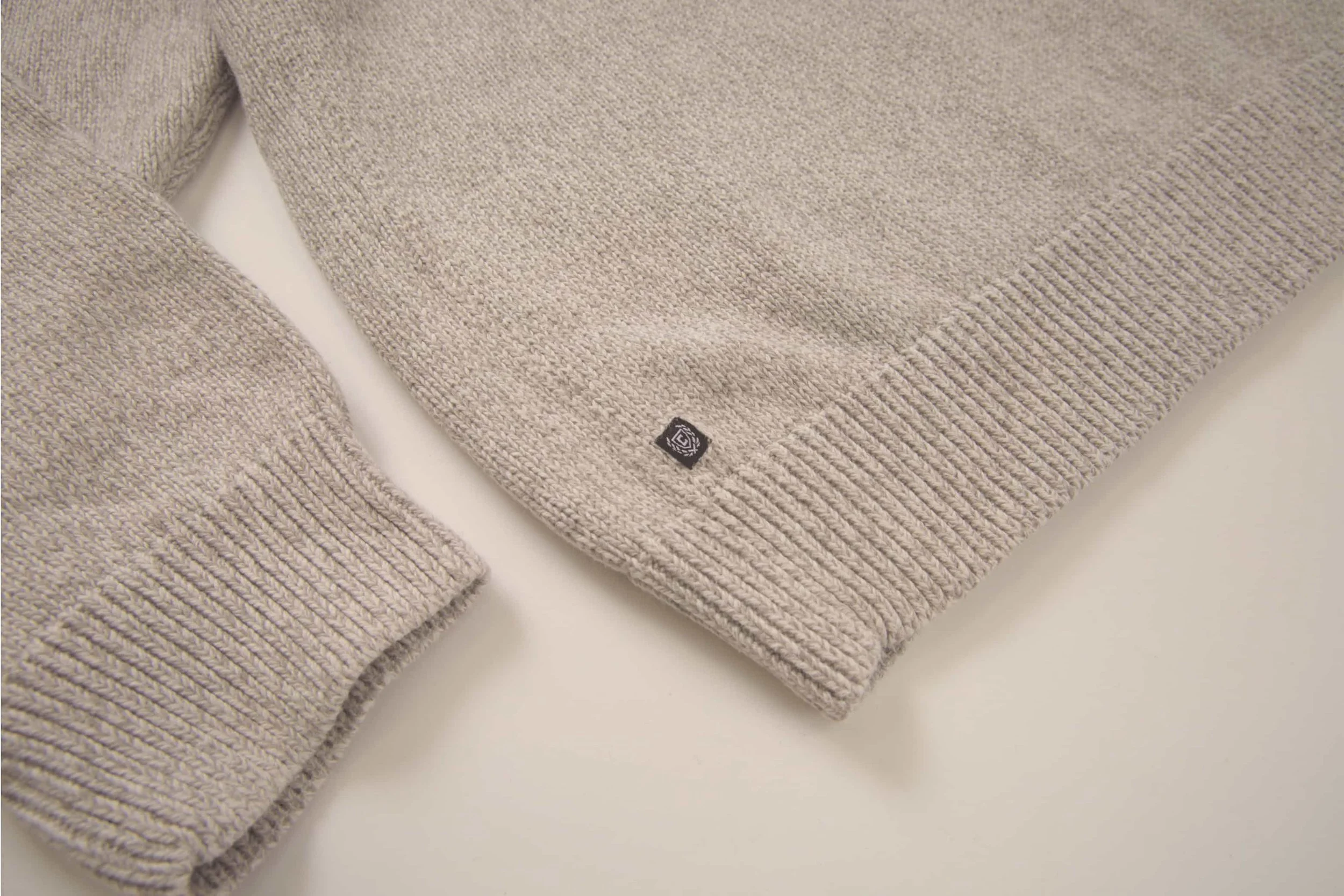 Speckled Grey / Beige vintage sweater with a small black logo tag near the hem.